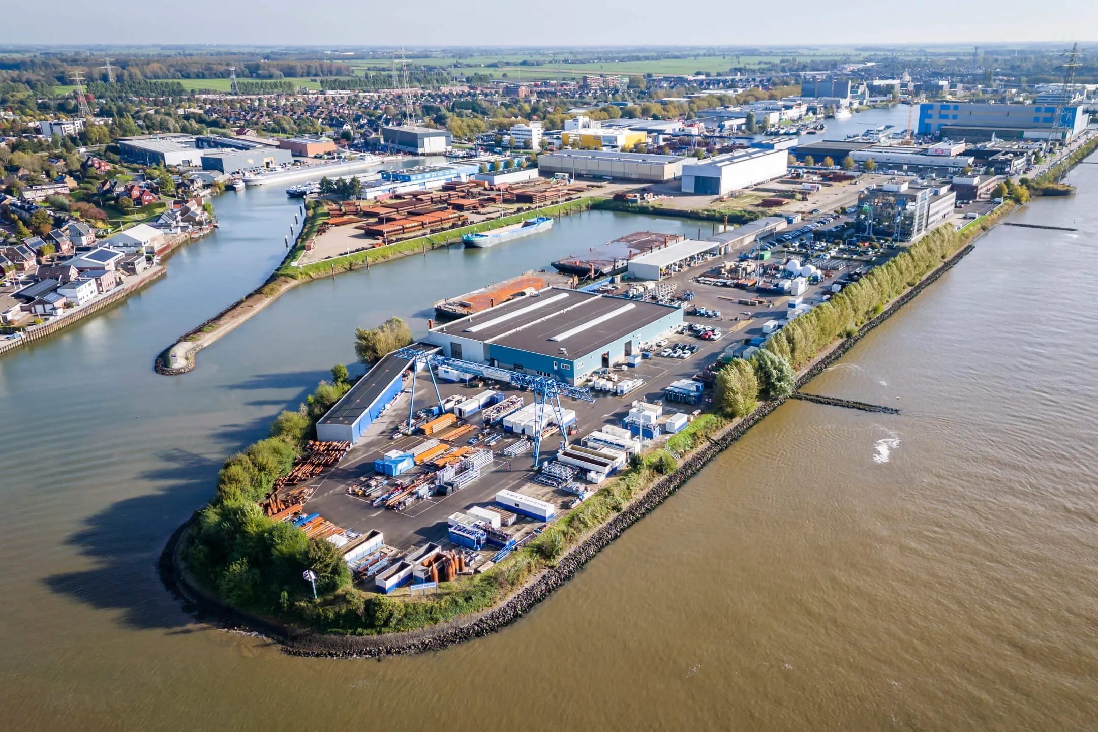 Aerial view of industrial facilities and storage containers on a peninsula surrounded by water.