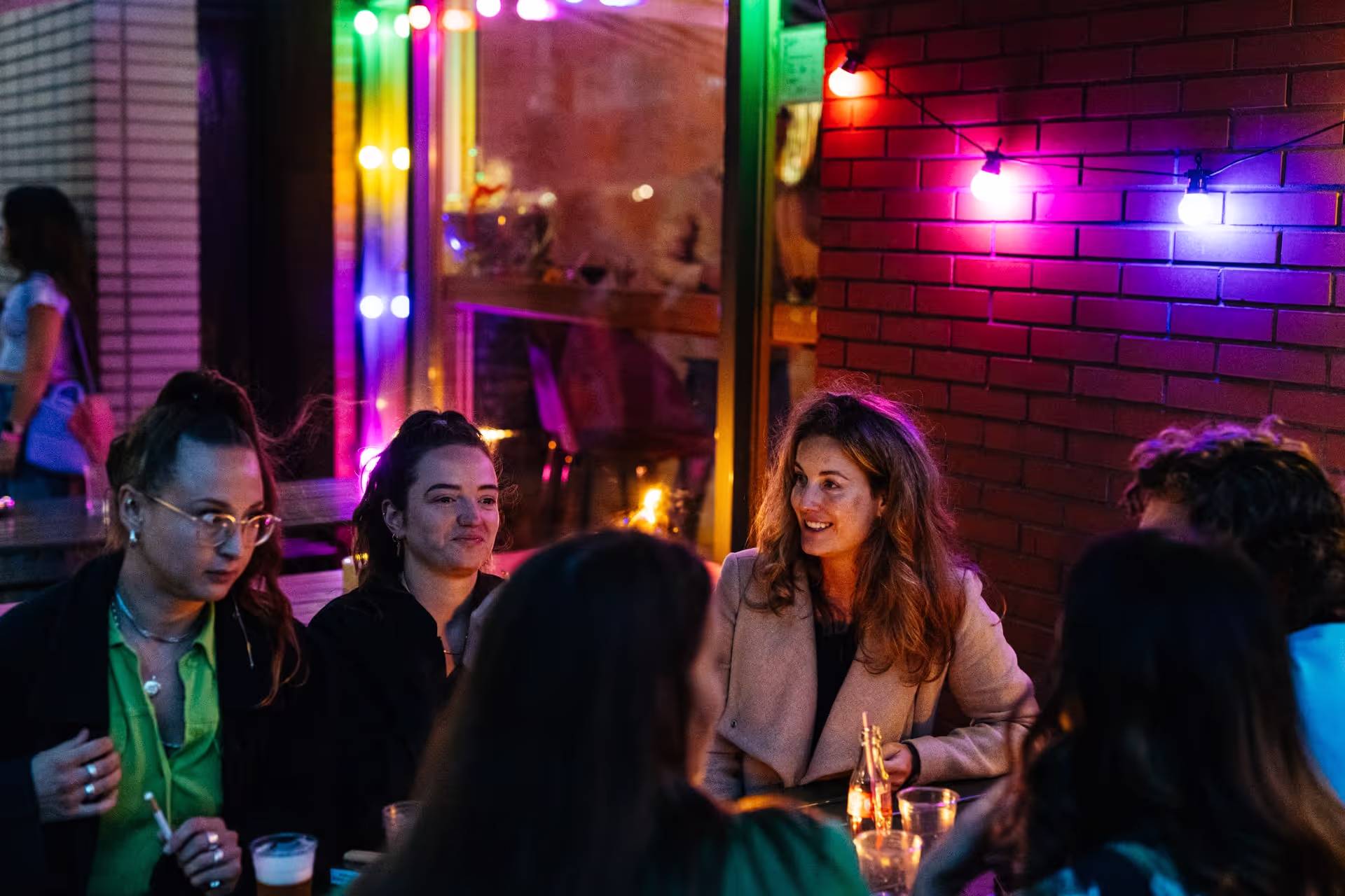 Groep vrienden geniet van drankjes en hapjes aan tafel tijdens een gezellige borrel in Amsterdam.