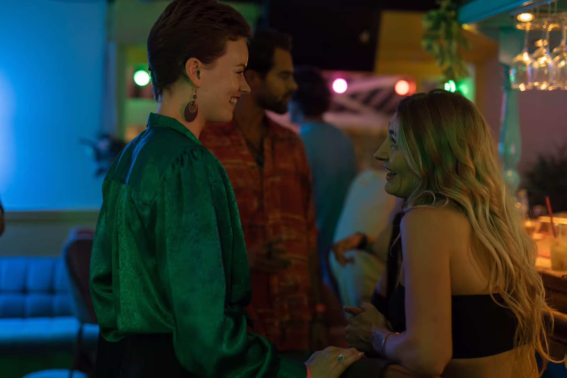 Twee vrouwen praten met elkaar tijdens een feest in een sfeervolle bar in Amsterdam.