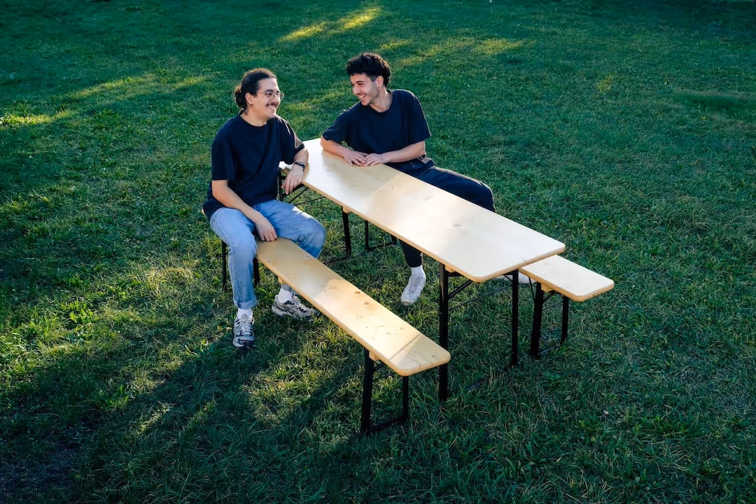 Bierbank-Flitzer Jonas und Valentin sitzen auf einer Bierbank im Sonnenlicht.