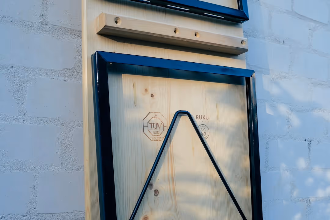 Rückansicht einer Bierbank aus Holz vor einer weißen Wand mit Blick auf den Klappmechanismus.