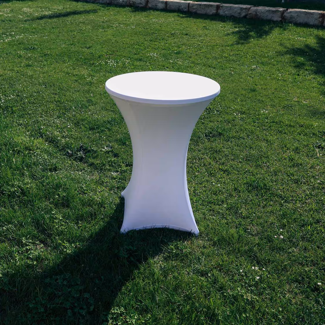 Stehtisch in weißer Husse auf einer grünen Wiese.