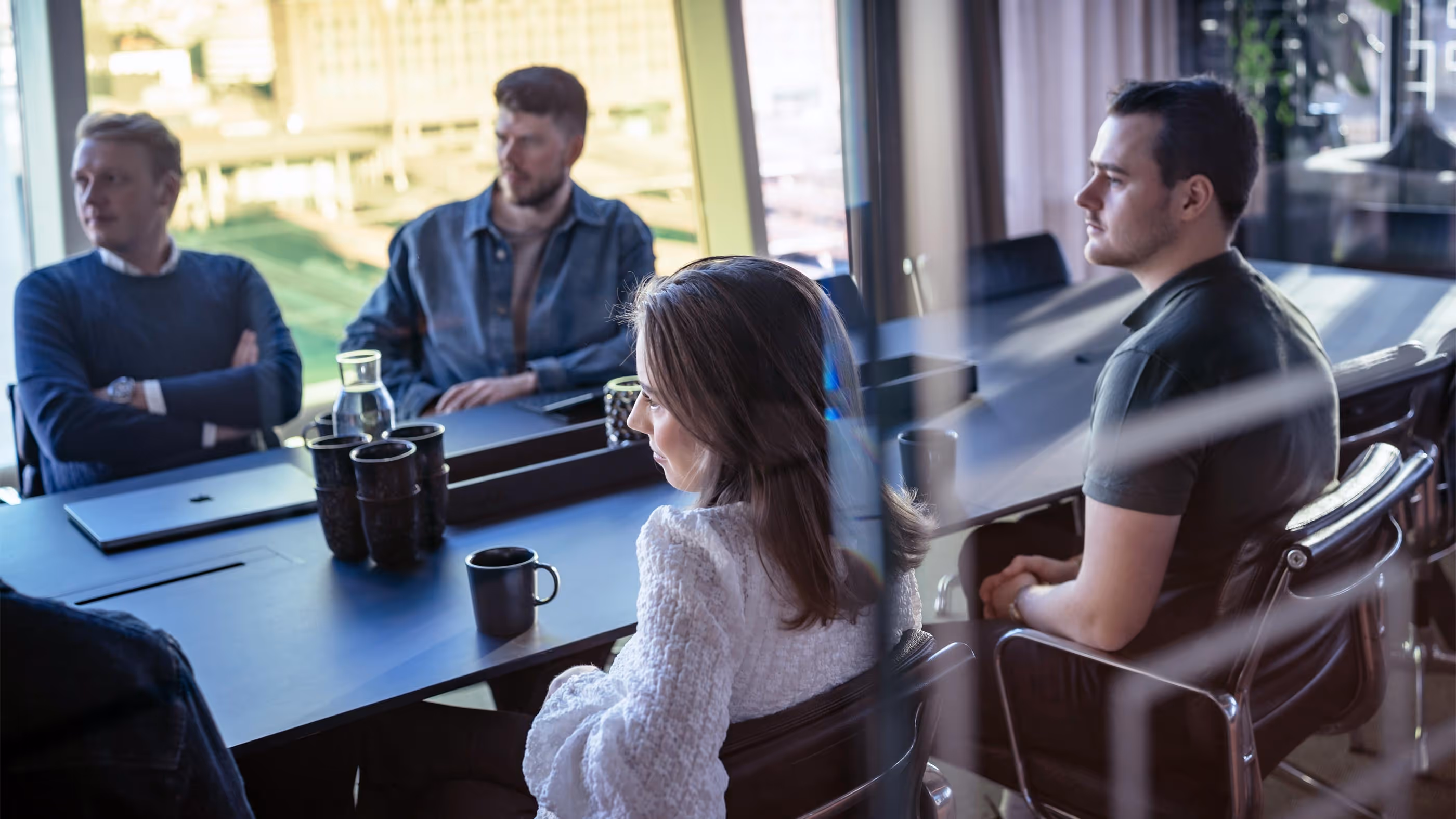 Fire personer sitter rundt et konferansebord