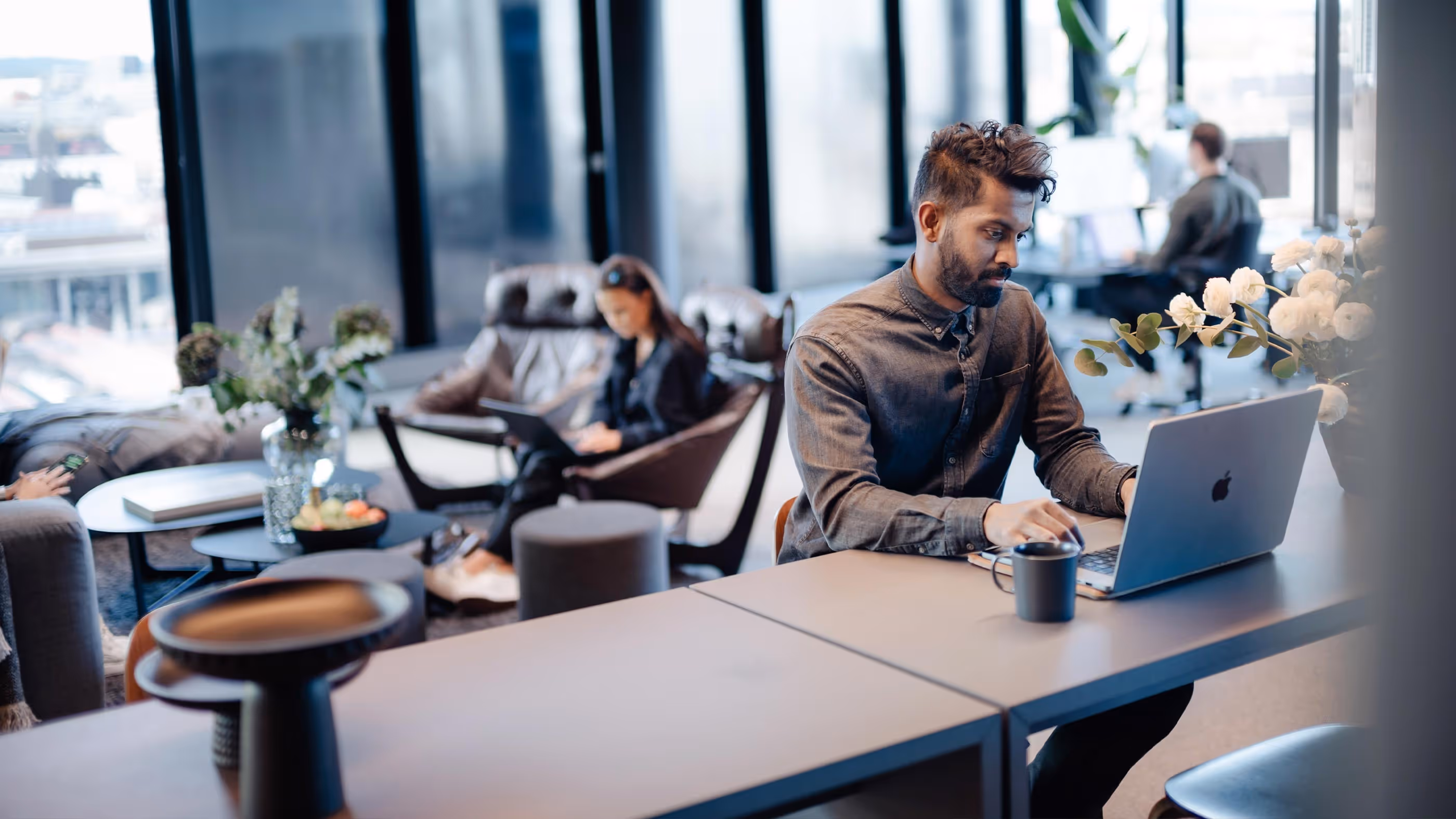 Man sitter foran en laptop i et kontorlandskap