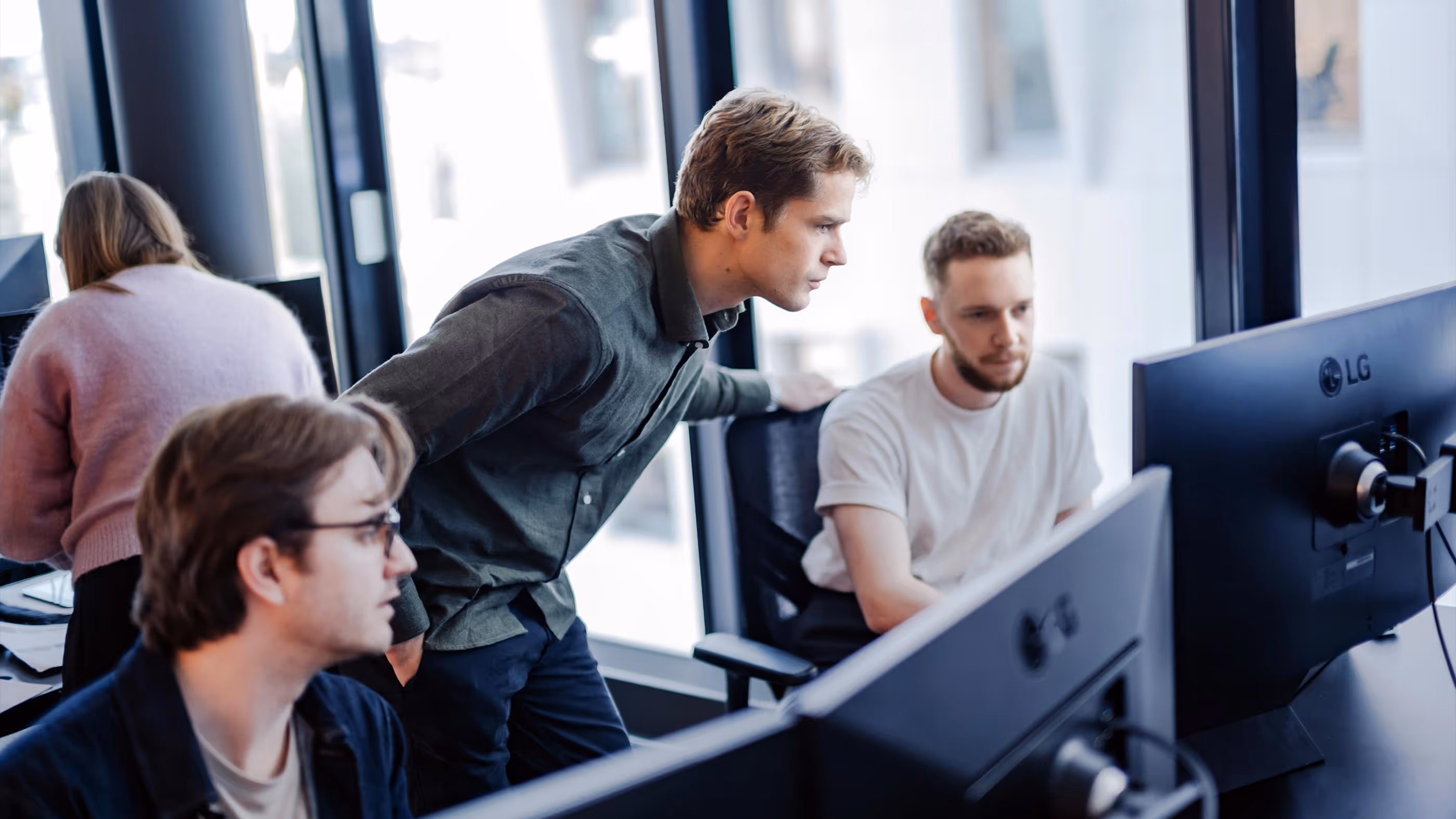 Tre utviklere ser på en dataskjerm