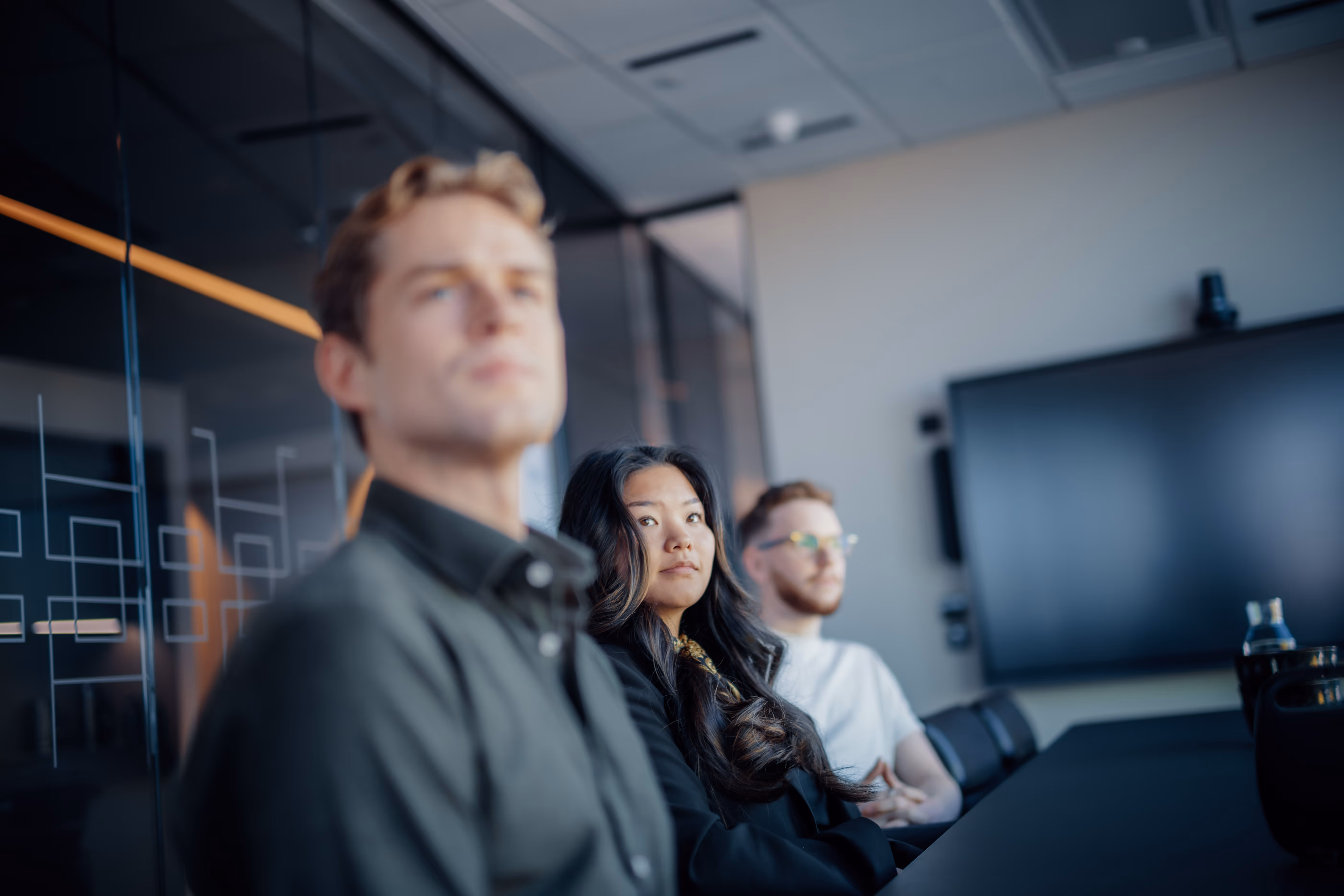 Kvinne smiler mot kamera med teams på storskjerm i bakgrunnen