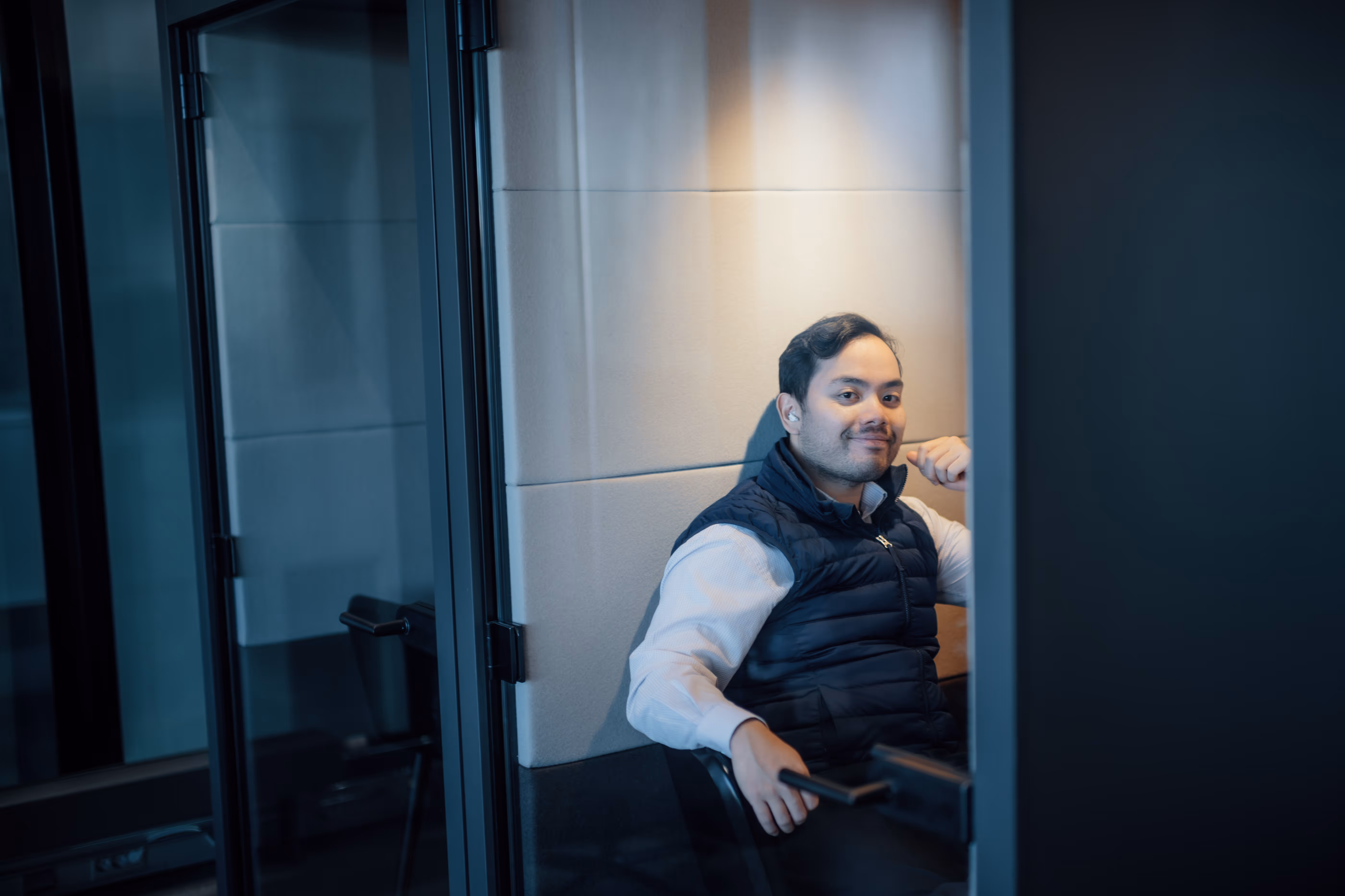 Kvinne smiler mot kamera med teams på storskjerm i bakgrunnen