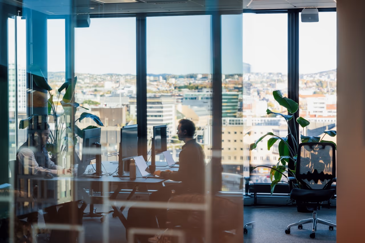 Fire personer sitter rundt et konferansebord