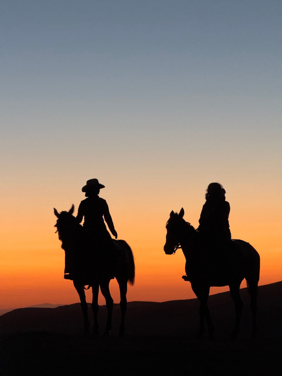 Silhouettes of two riders at sunset
