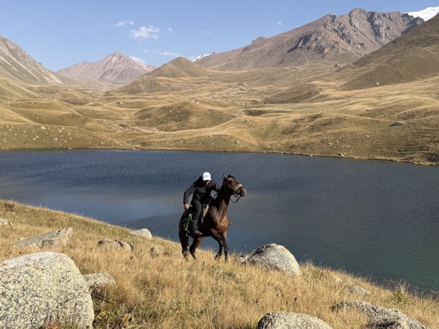 Rider by a mountain lake on the summer pasture