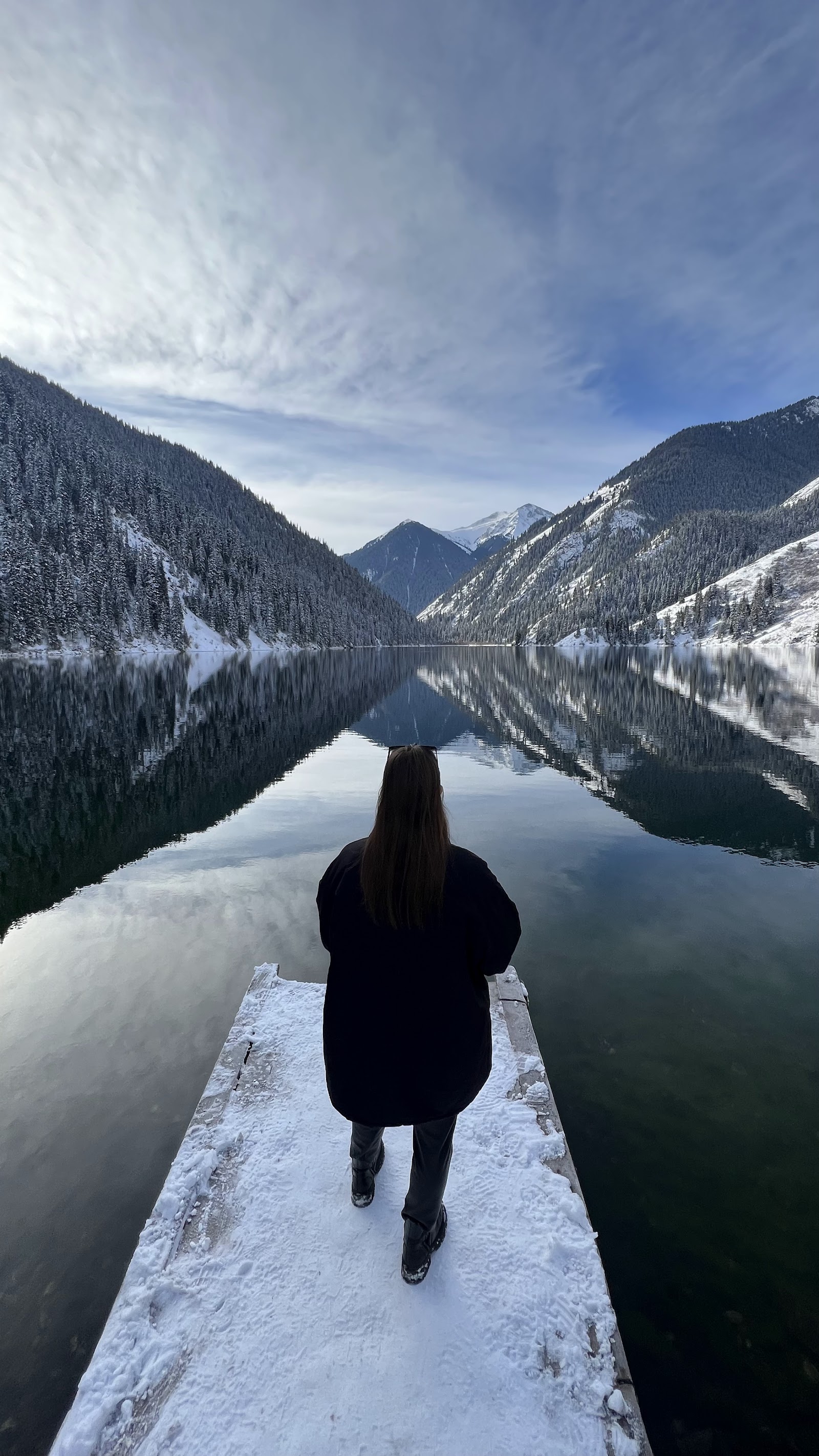 Lake Kolsay in winter, snowy jetty and fir-covered mountains
