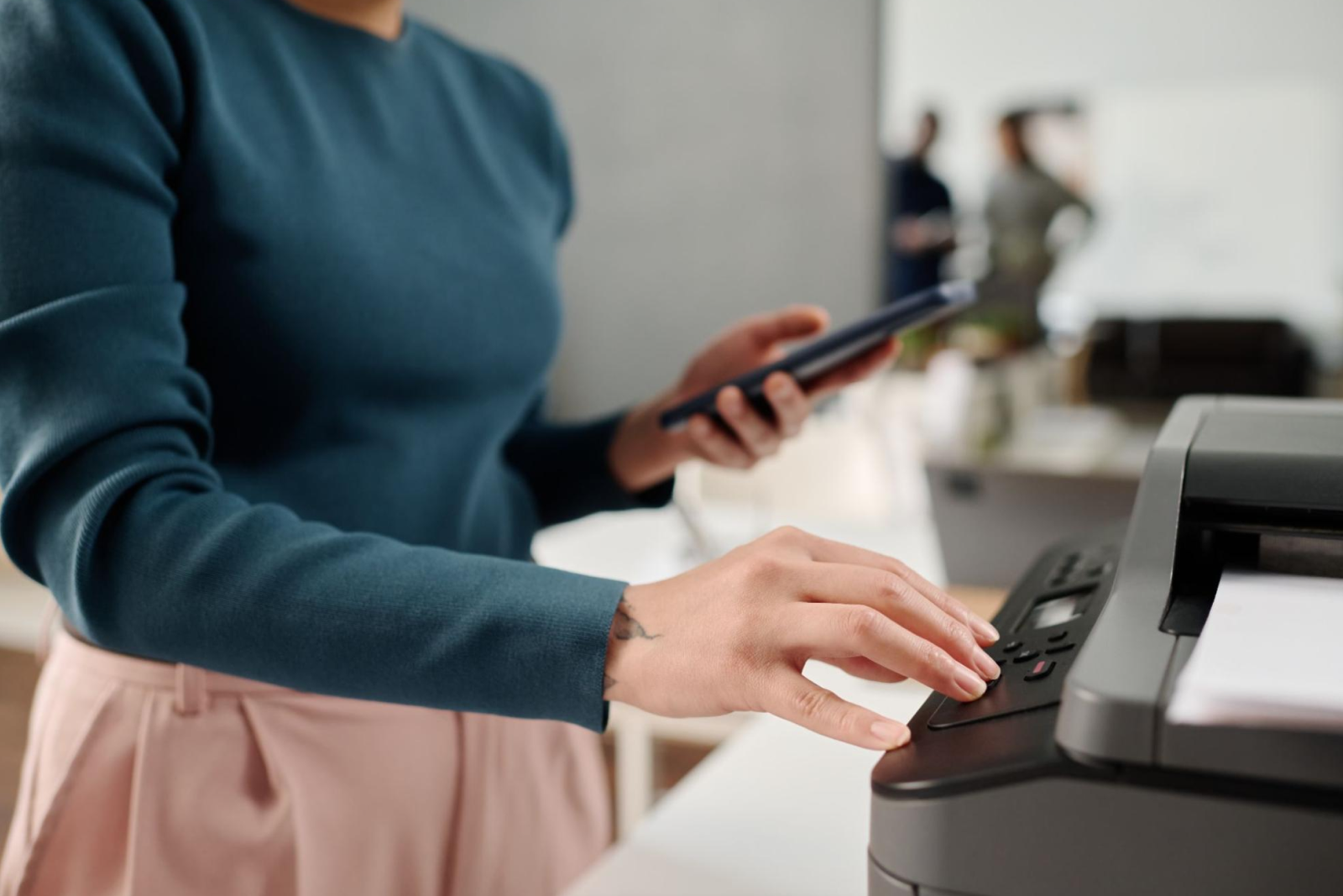 Unrecognizable office worker in a green sweater using a printer. 