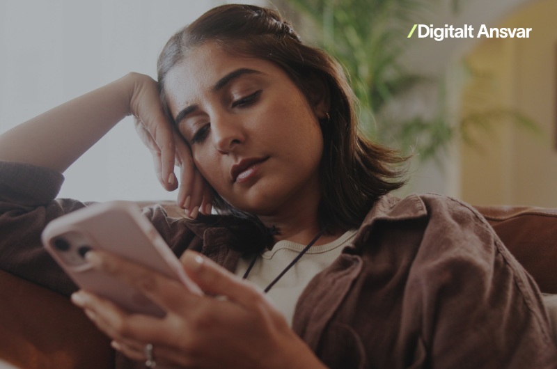 en person sidder i en sofa og igger på en smartphone