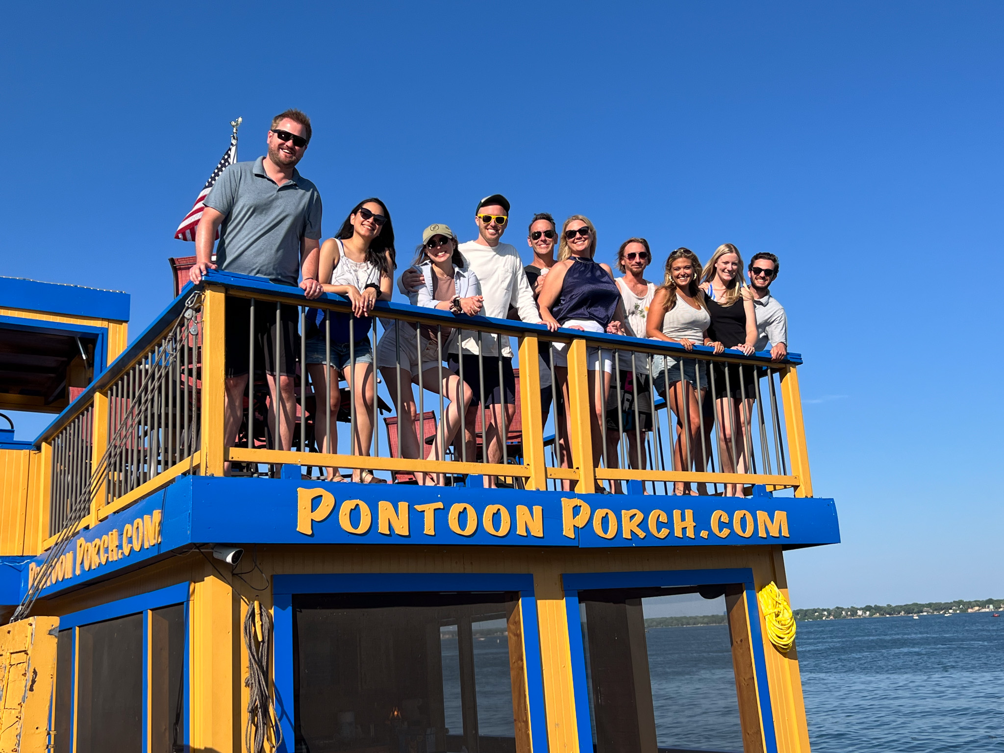 The U.S. Market Crafters team standing on the balcony of Pontoon Porch boat during the 2023 summer outing.