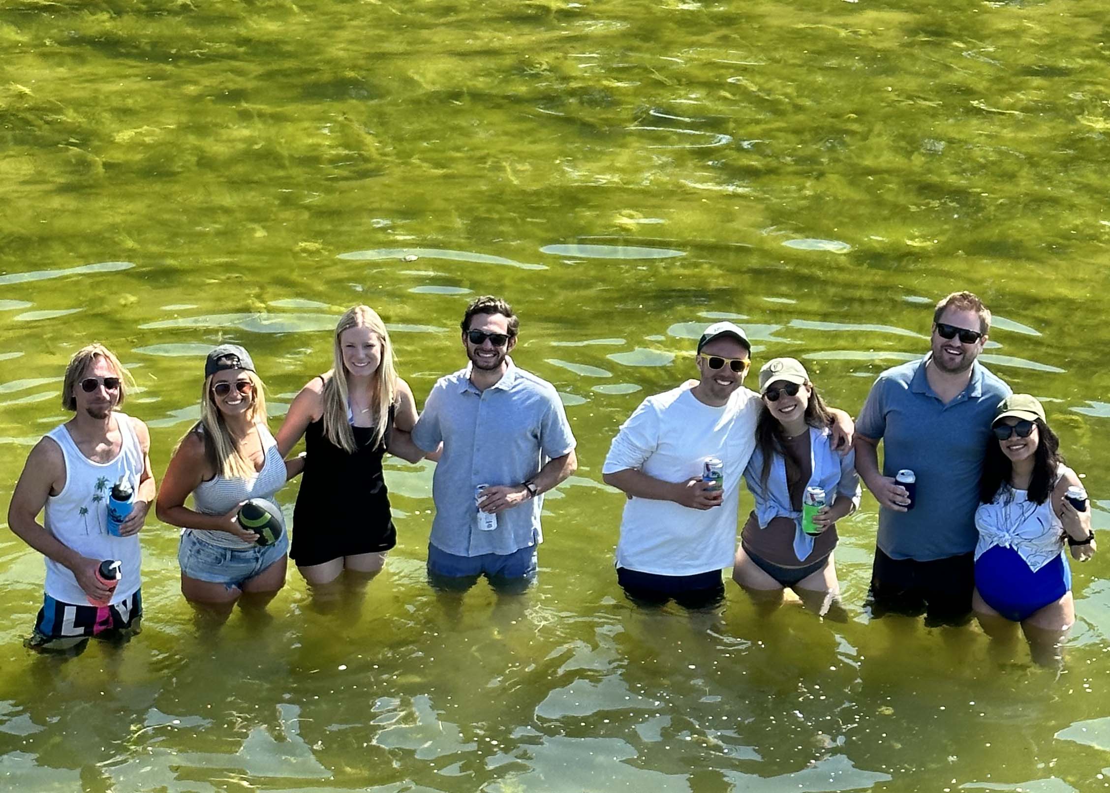 The U.S. Market Crafters team standing in the water at the summer Pontoon Porch outing.