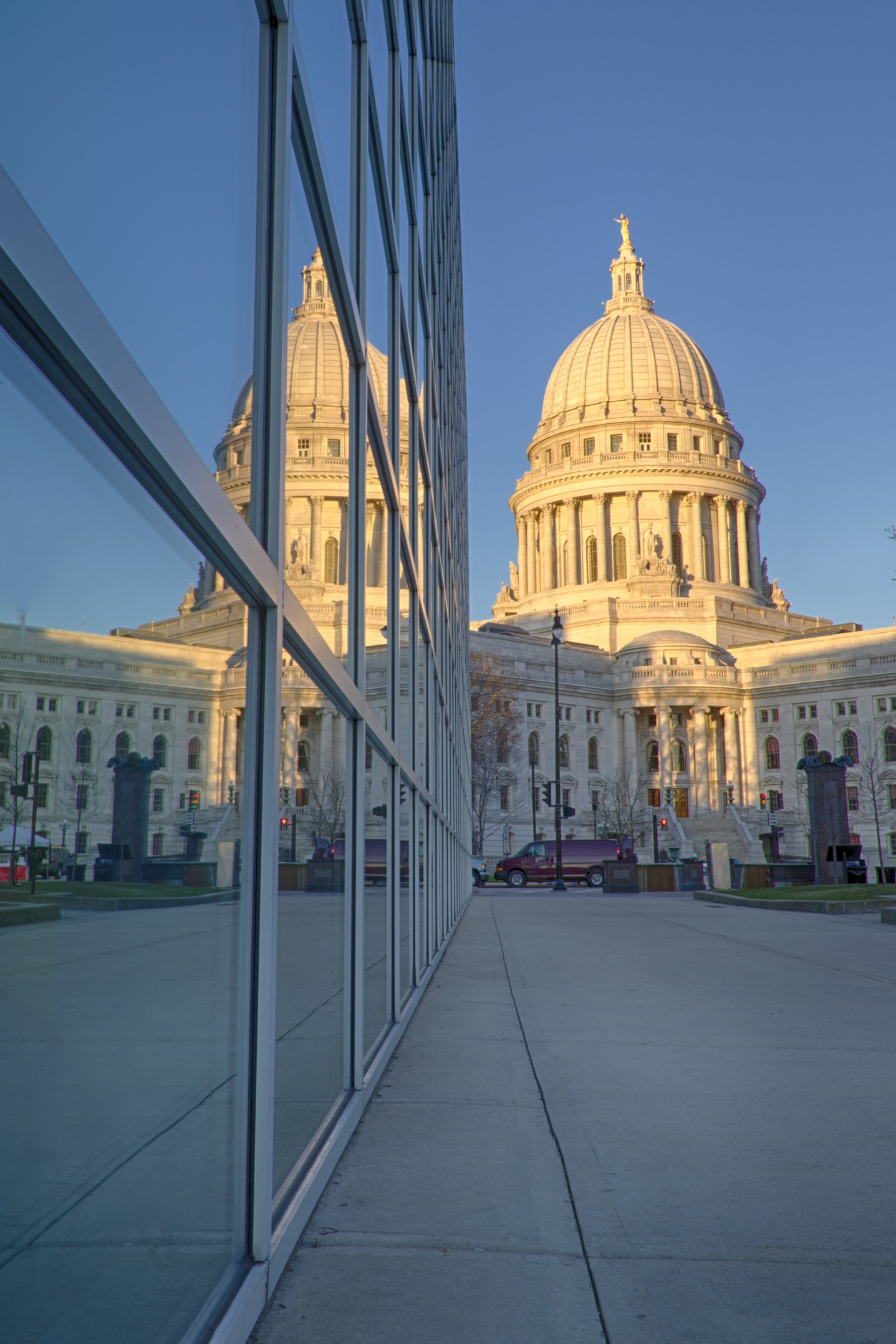 Down town Madison Wisconsin shows a reflection of the state capitol building in the window of a building.