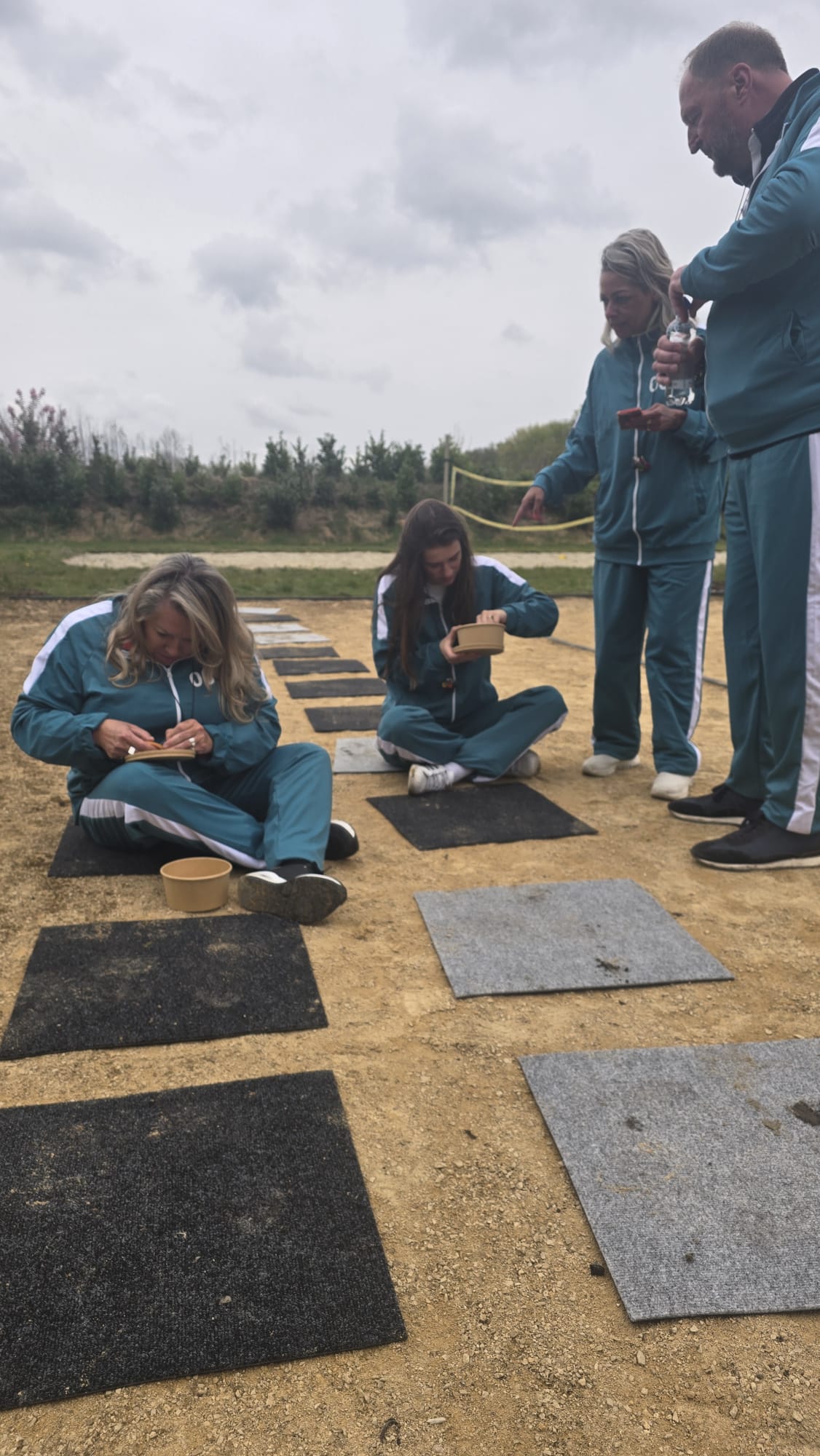 Twee dames zitten op de grond en voeren een Squid Game opdracht uit