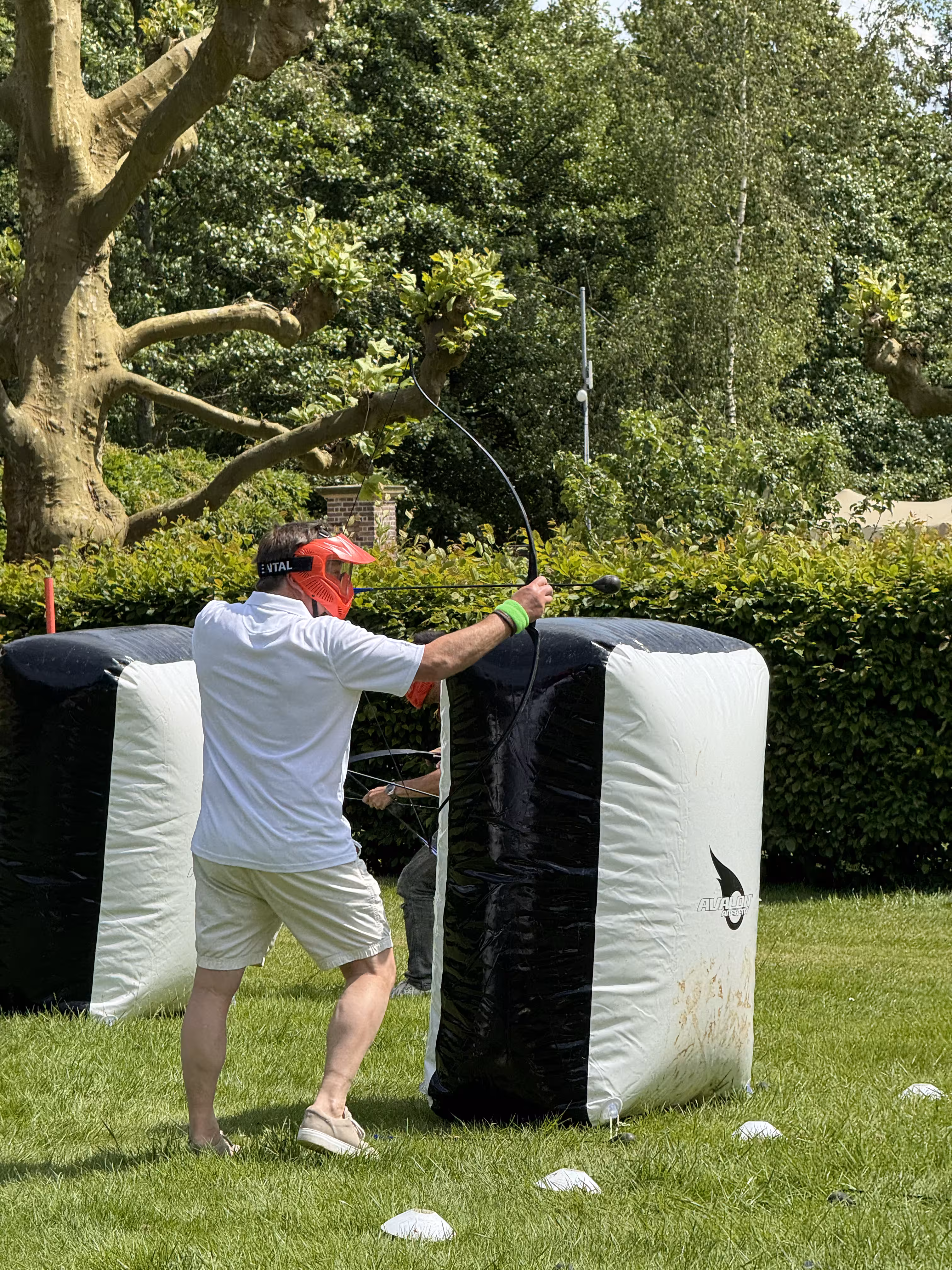 Een man met met zomers outfit schiet met pijl en boog tijdens de Archery Tag Workshop