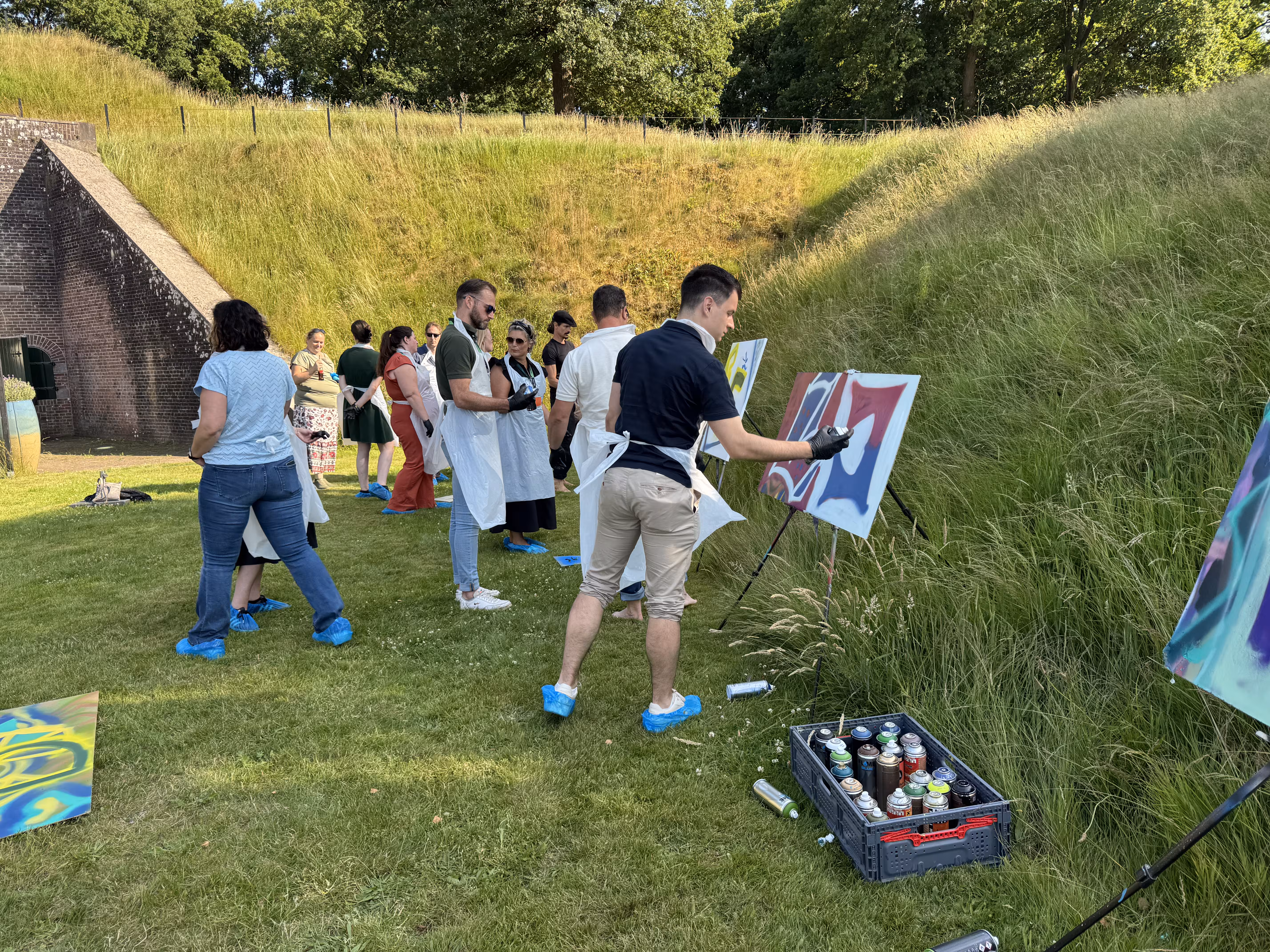 Op een grasveld bij Fier Bussem zijn de deelnemers bezig met een graffiti workshop