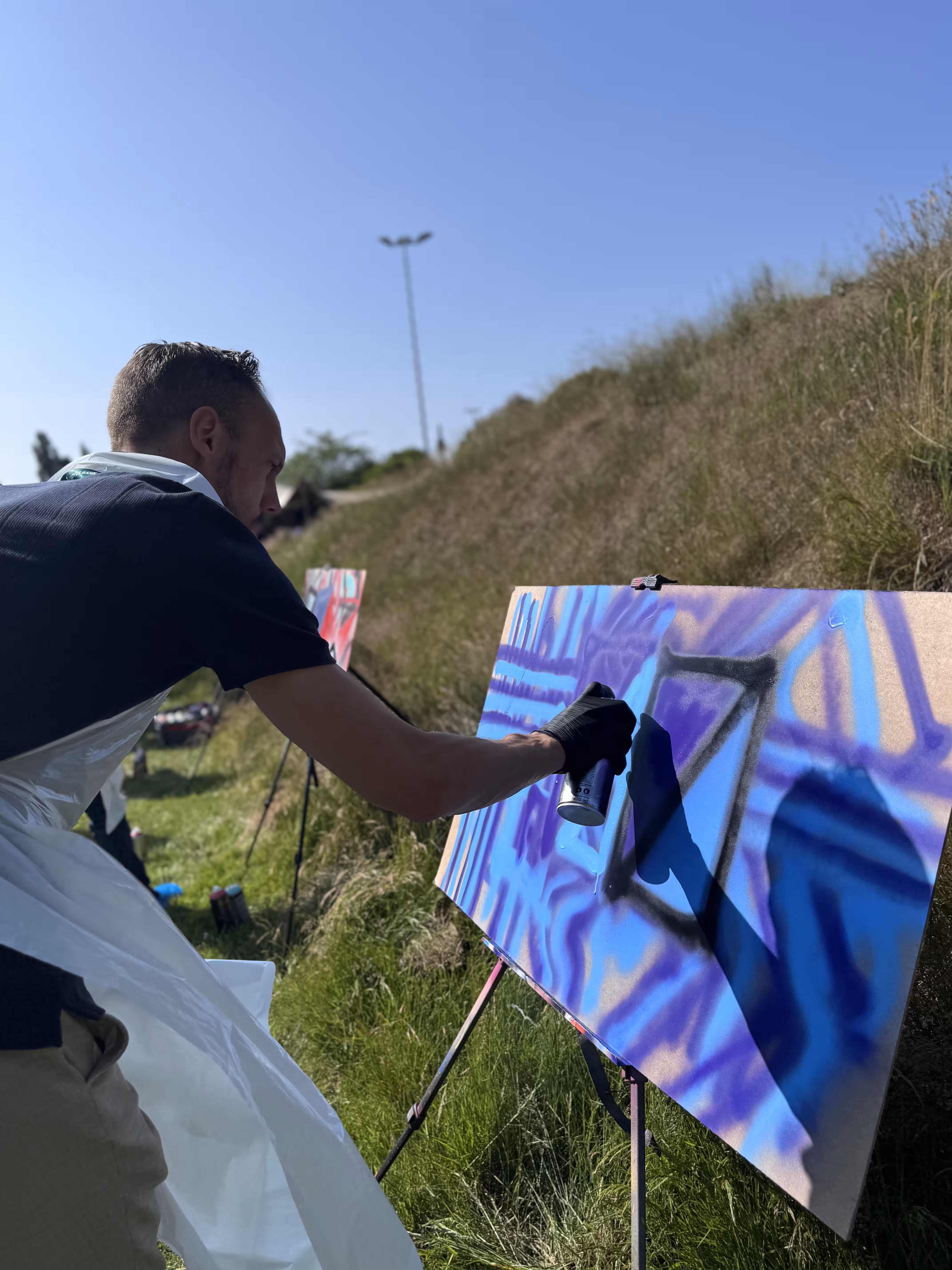 Een close up van een man die met blauw en paarse verf aan het werk is