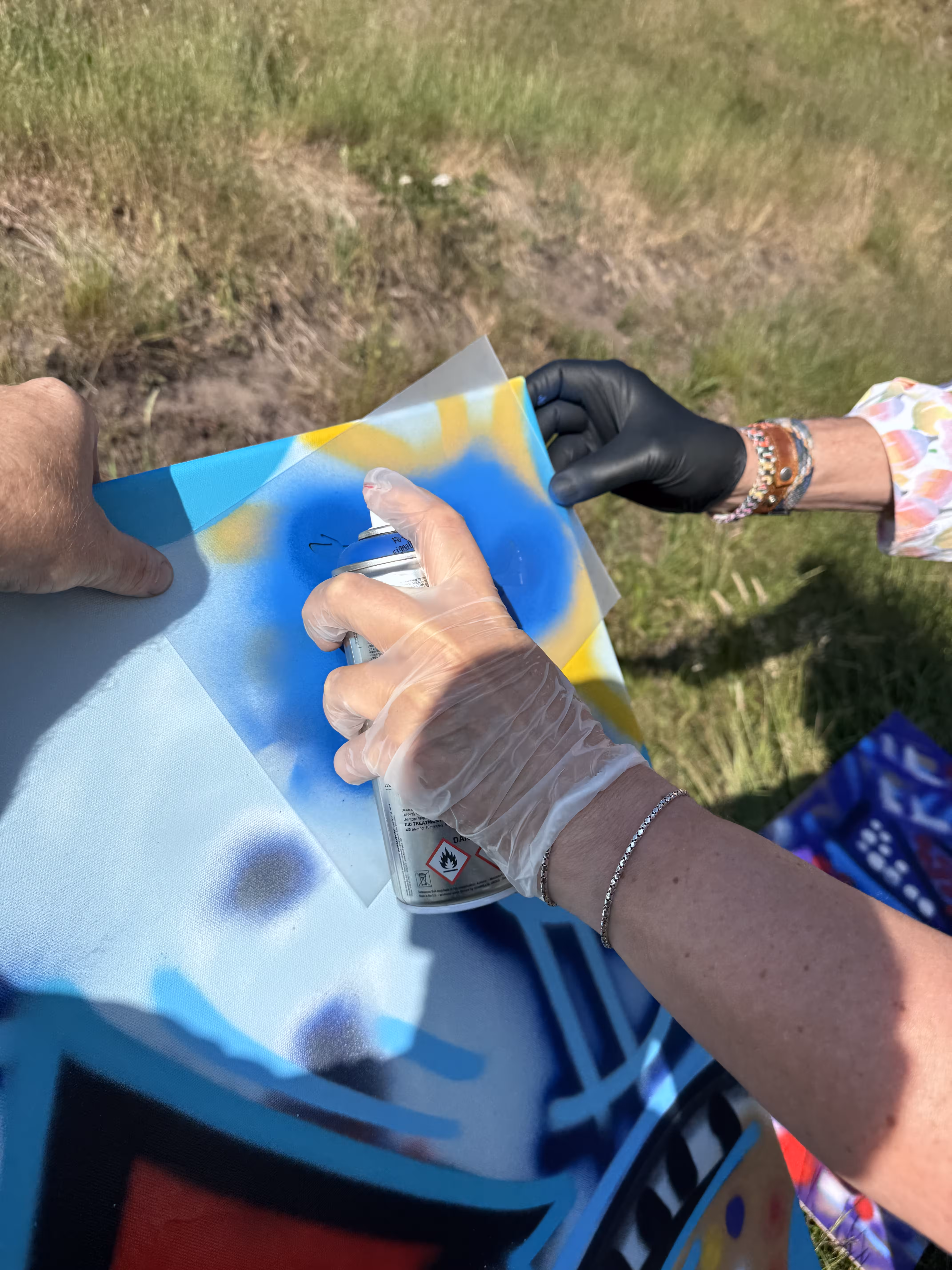 Close up van een hand met een plastic handschoen met een blauwe spuitbus