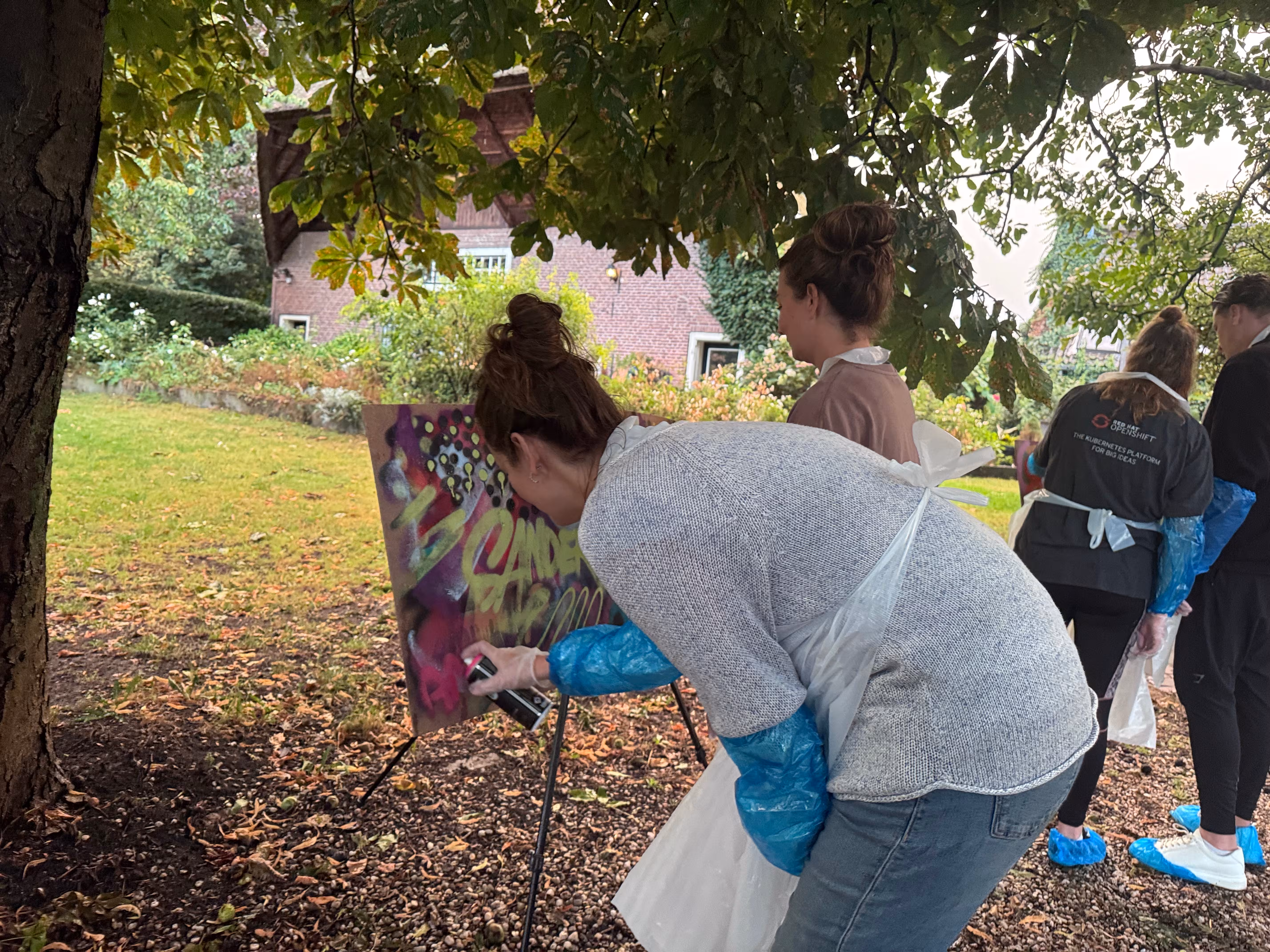 Er wordt met roze verf gewerkt door een mevrouw tijdens de graffiti workshop in een natuurlijke omgeving