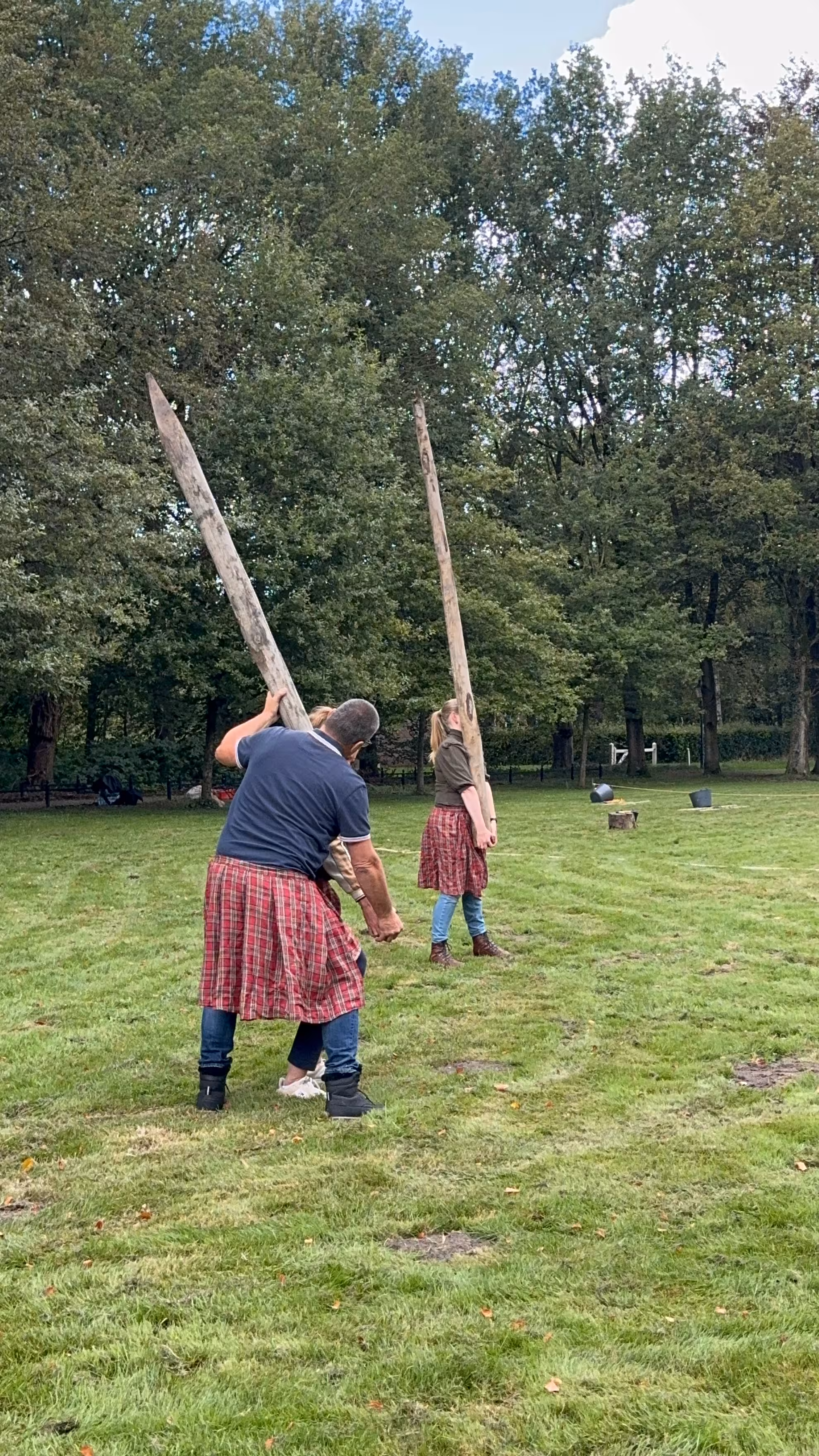 Twee houten palen worden in de lucht gehouden door deelnemers van de Highland Games