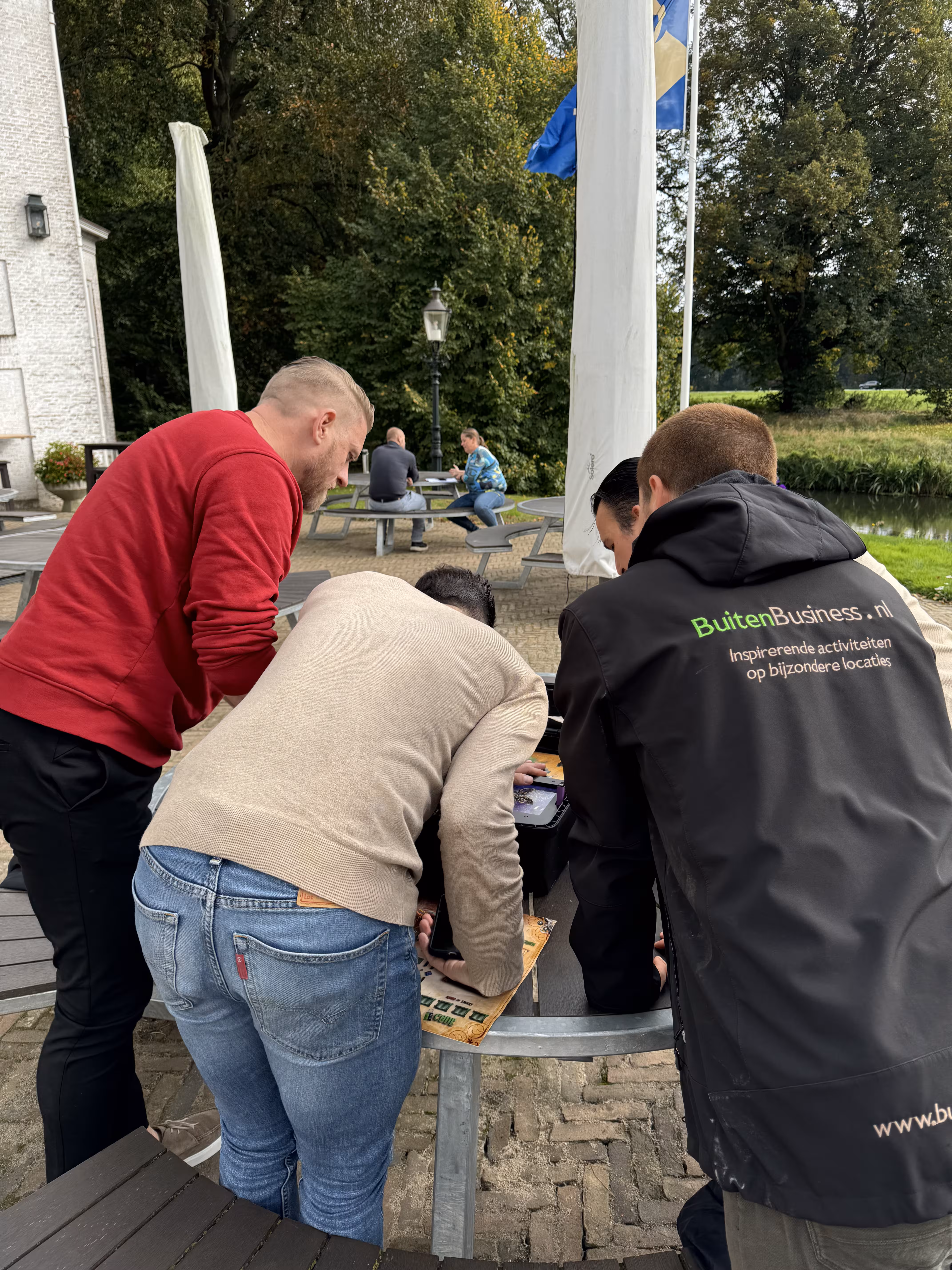 De BuitenBusiness instructeur kijkt mee met drie personen tijdens de Escape Game