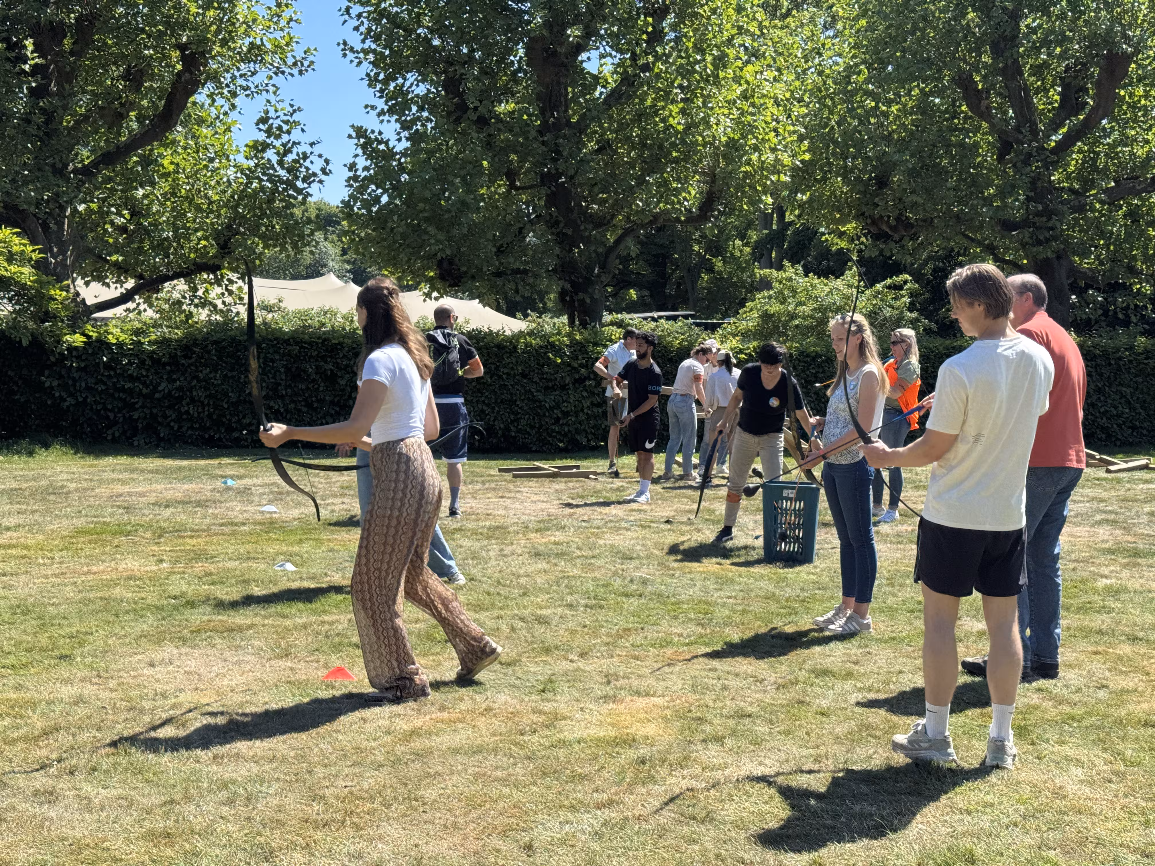 Er wordt op een grasveld op een zonnige dag geschoten met pijl en boog
