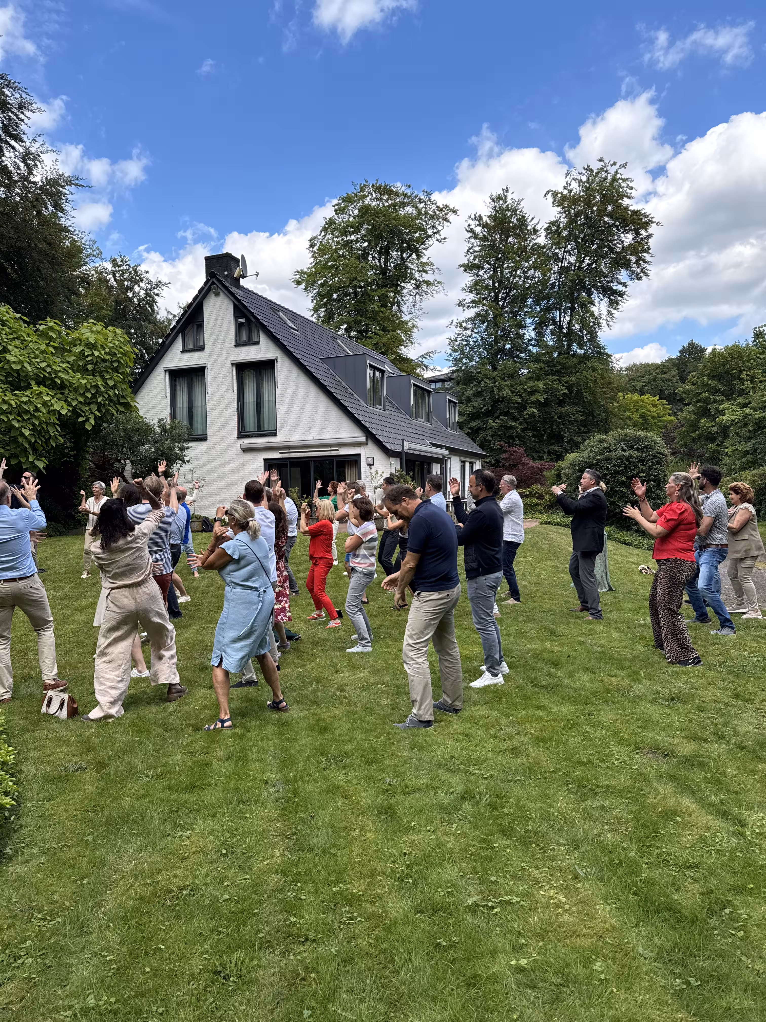 Op een grasveld voor een wit huis wordt een HAKA workshop door BuitenBusiness verzorgd