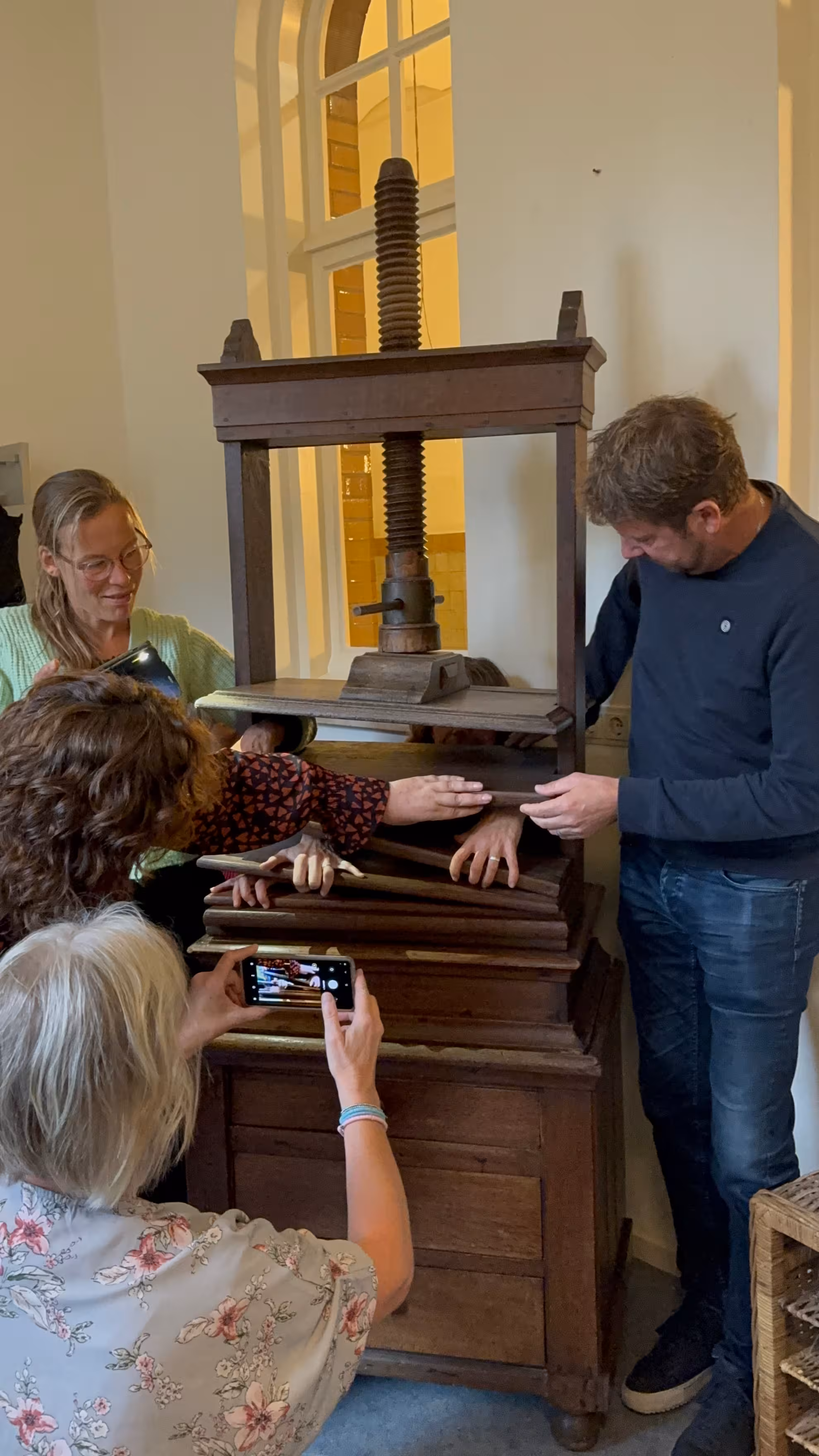 Bij een houten kast wordt een foto gemaakt met een telefoon van handen tussen de planken