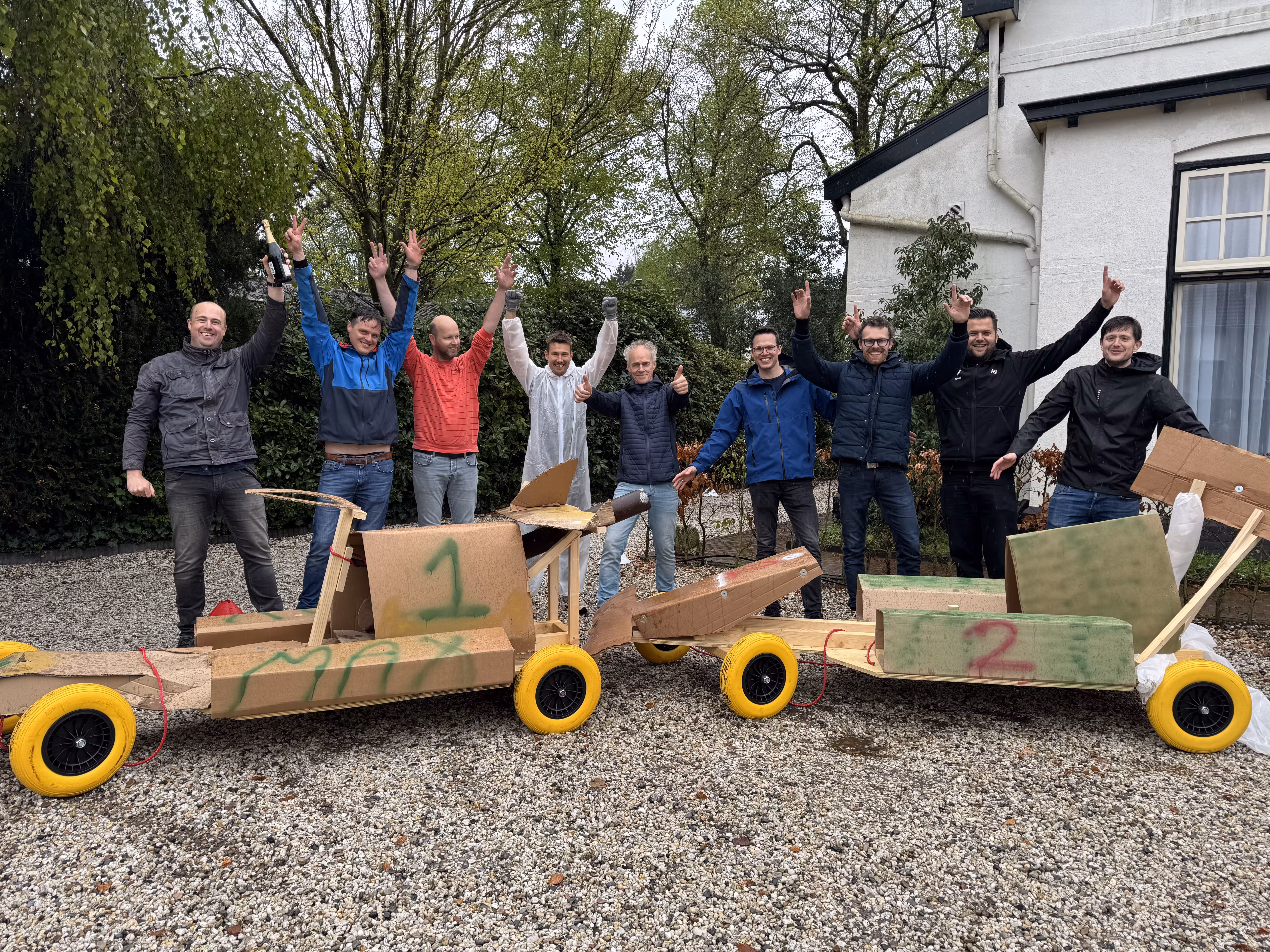 Negen mannen staan achter de twee formule 1 wagens die zijn gebouwd