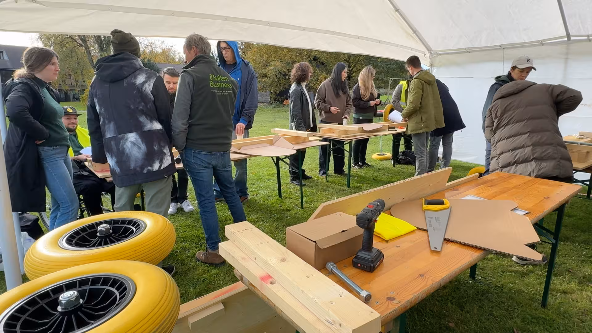 In een witte tent wordt aan biertafels gewerkt aan het maken van een eigen Formule 1 wagen