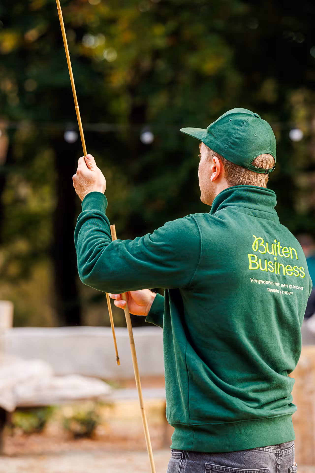 BuitenBusiness instructeur legt uit hoe er twee bamboe stokken aan elkaar bevestigd kunnen worden
