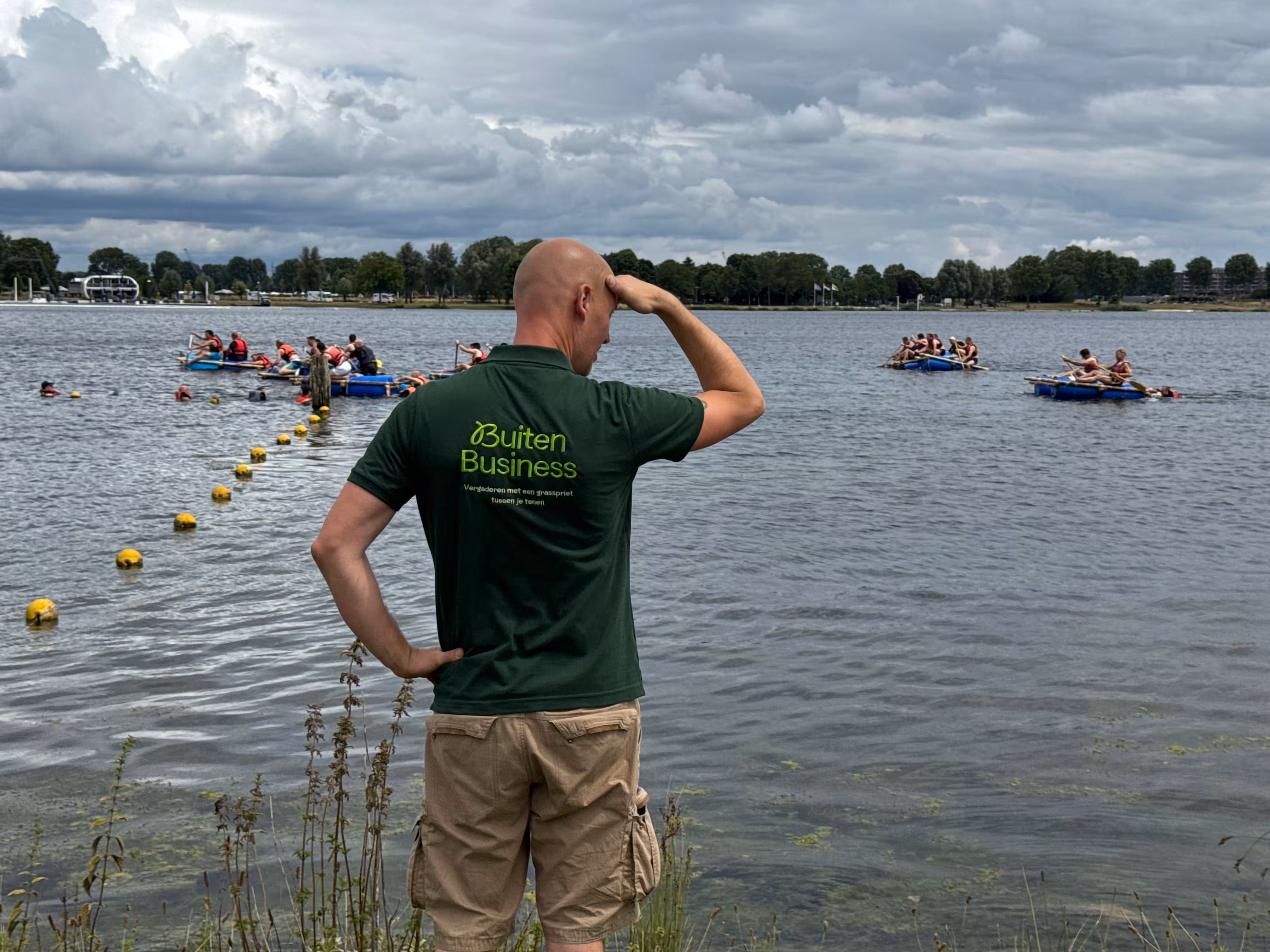 De BuitenBusiness instructeur kijkt richting de vlotten die op het water varen
