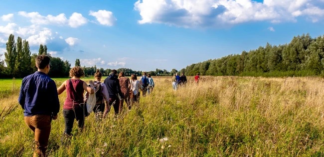 groep mensen loopt door het gras in de natuur