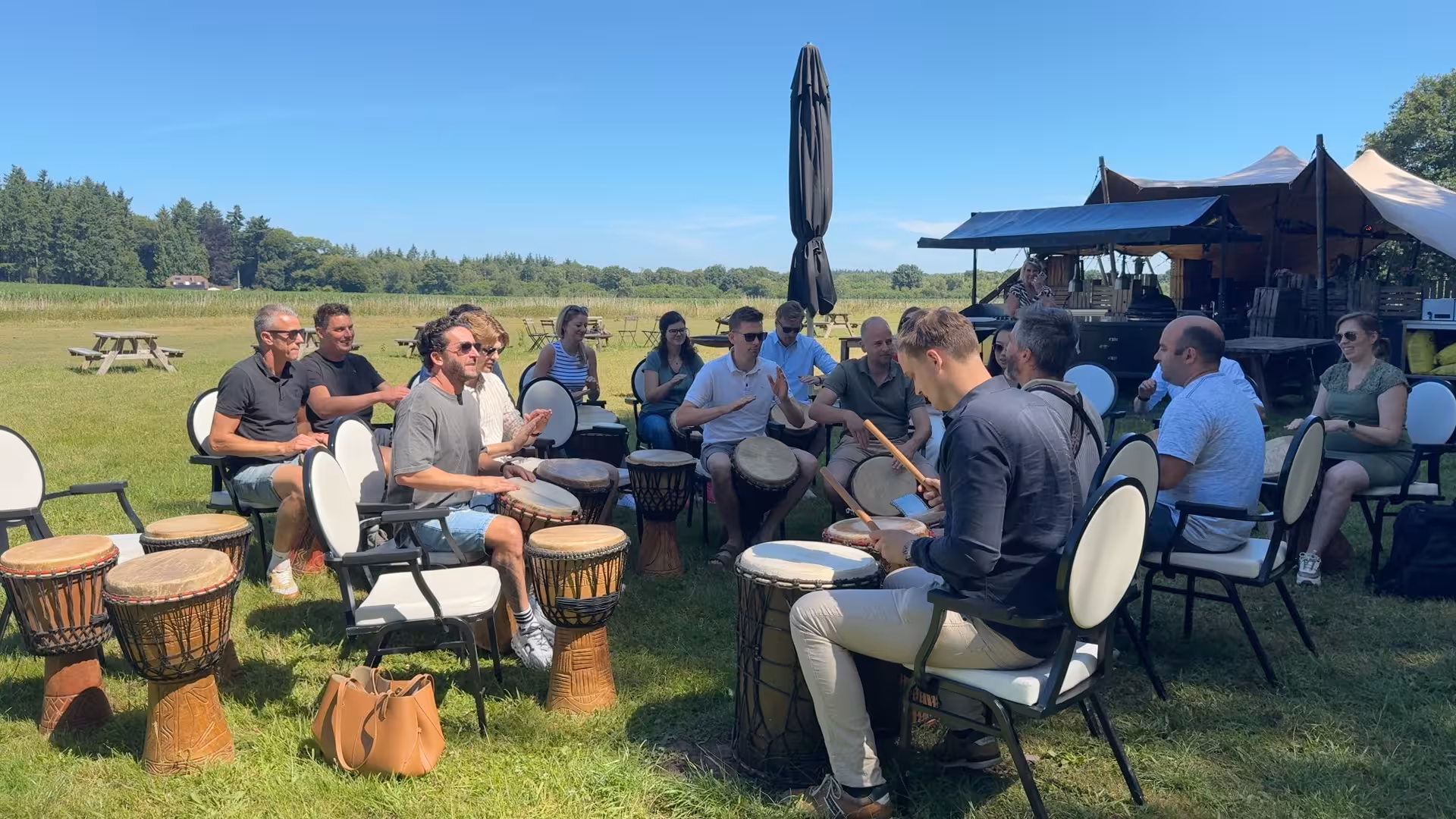 Zomerse dag op een grasveld, deelnemers nemen deel aan een Percussie workshop van BuitenBusiness