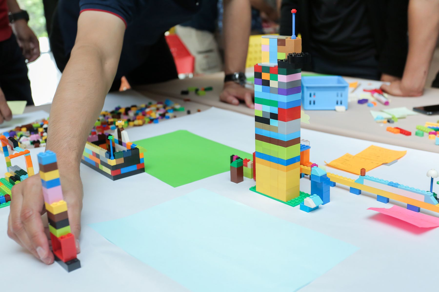 Iemand plaatst een toren van lego bij een bouwwerk van Lego Serious Play