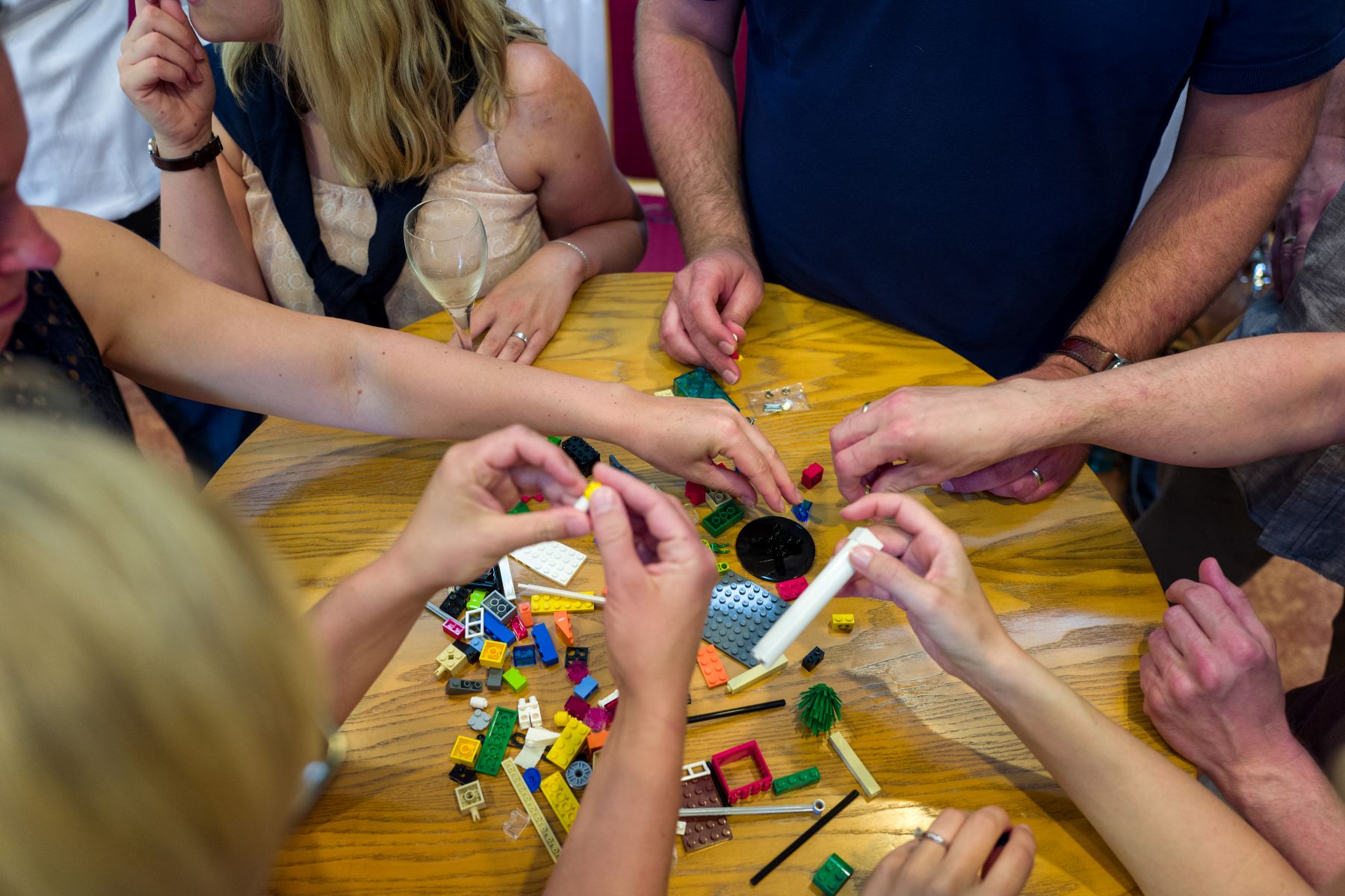 Verschillende mensen staan om een tafel en bouwen iets van Lego