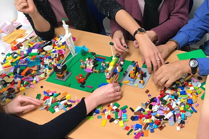 Groep mensen bouwt samen aan een bouwwerk met Lego Serious Play