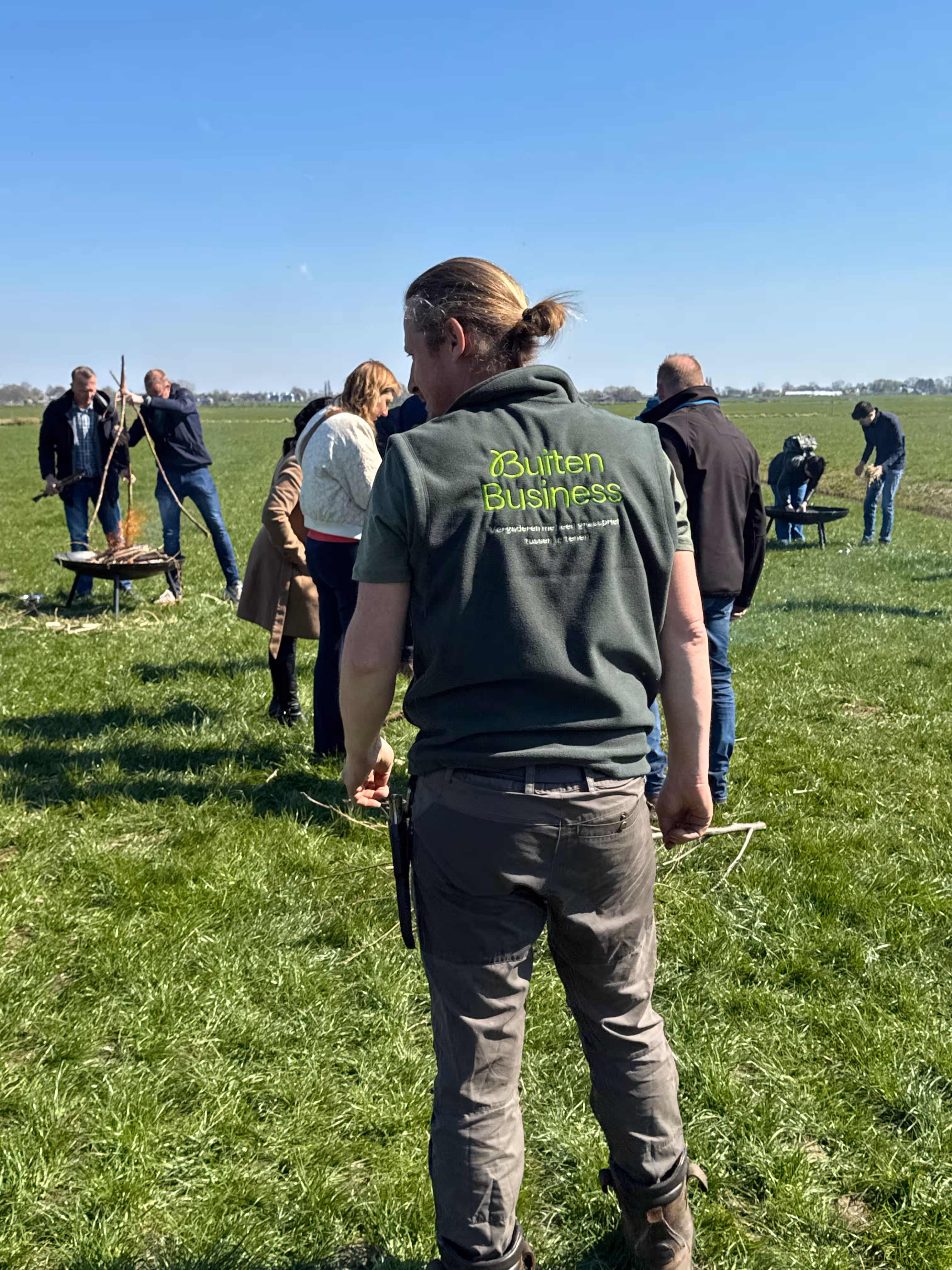 De BuitenBusiness instructeur kijkt toe naar de deelnemers tijdens de workshop vuur maken