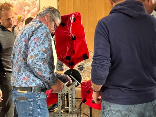 Een man bevestigd een onderdeel van de rode windmolen