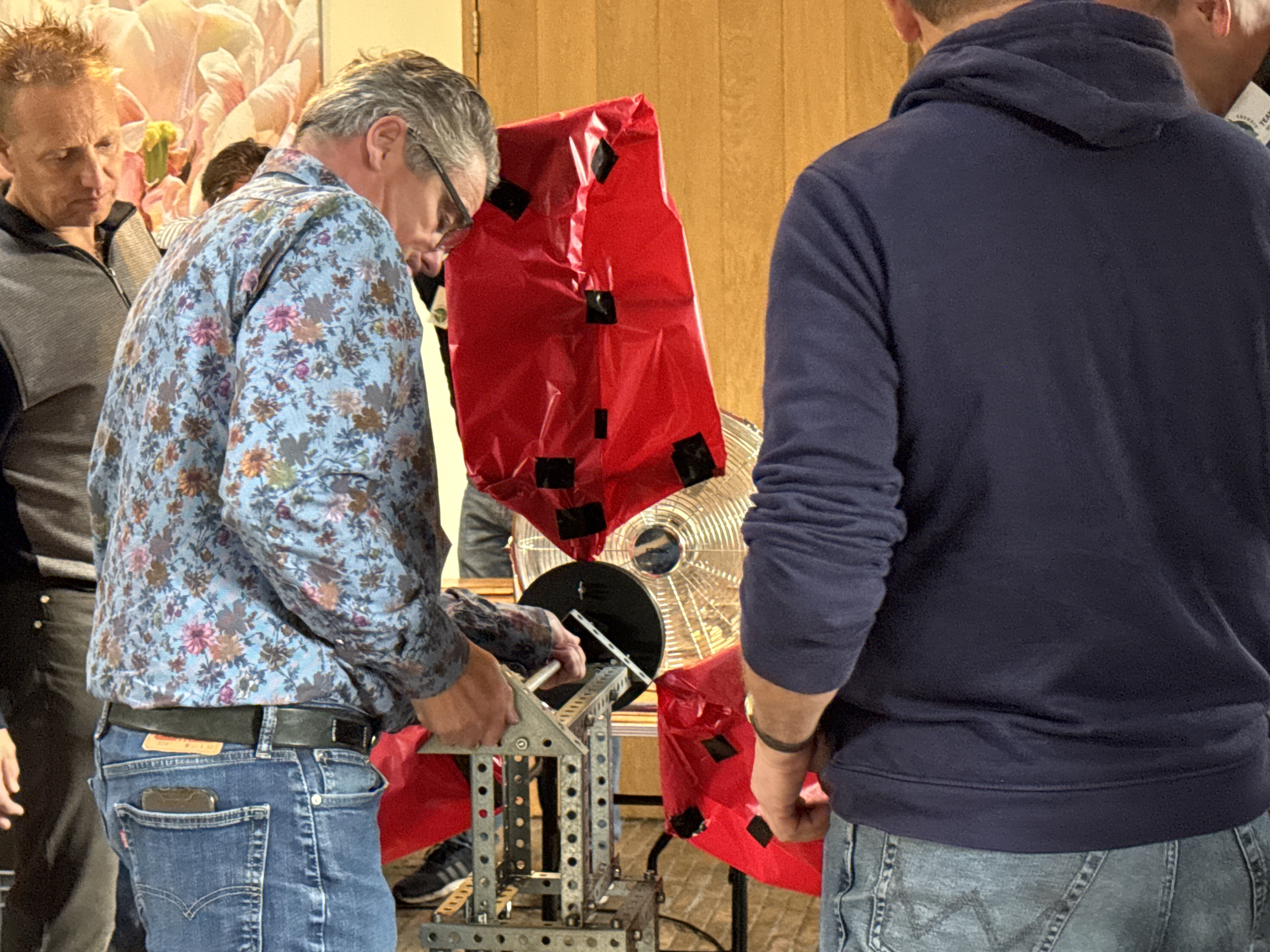 Een man bevestigd een onderdeel van de rode windmolen