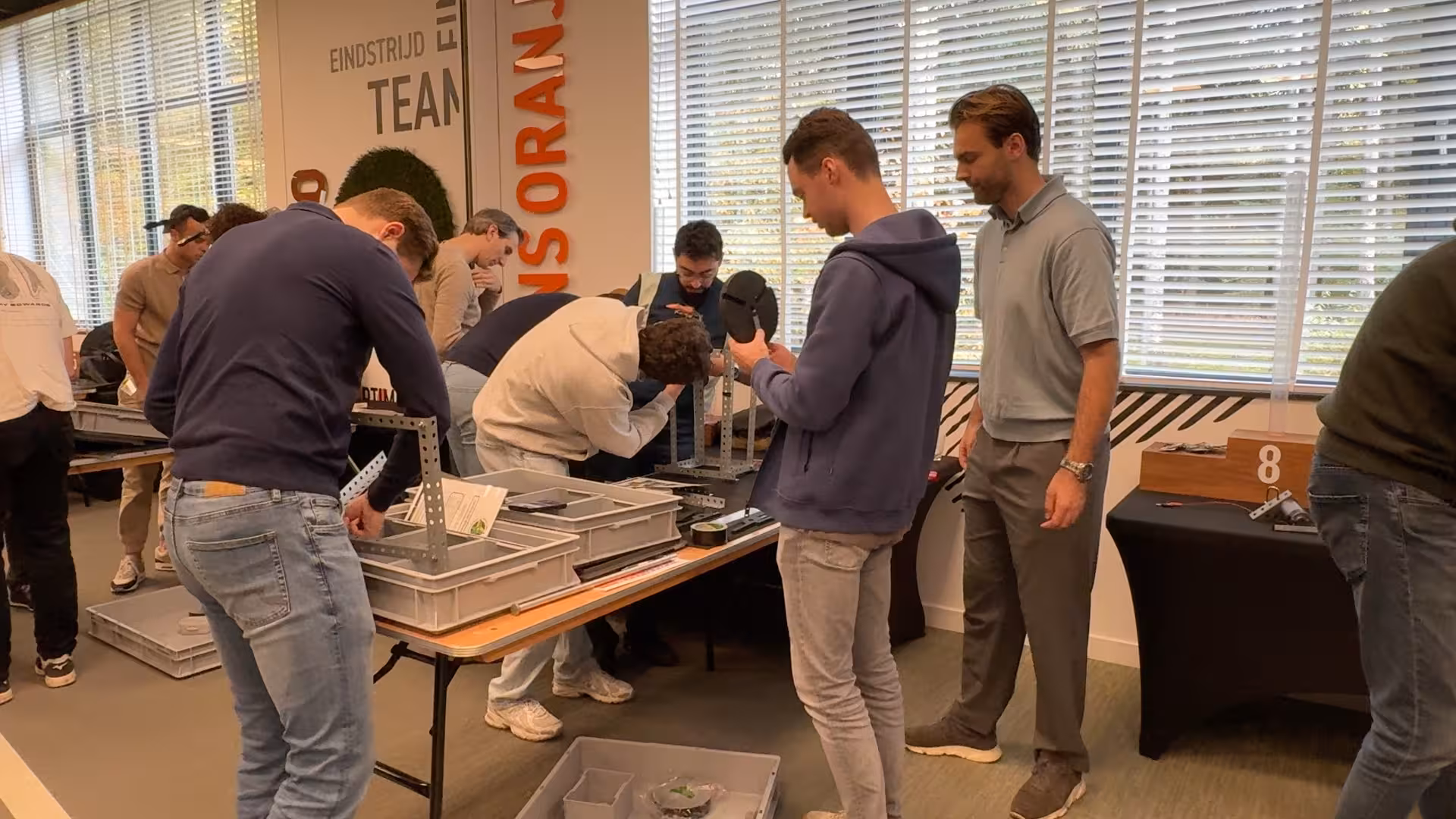 Aan een tafel werken verschillende mensen met materialen om een windmolen te bouwen