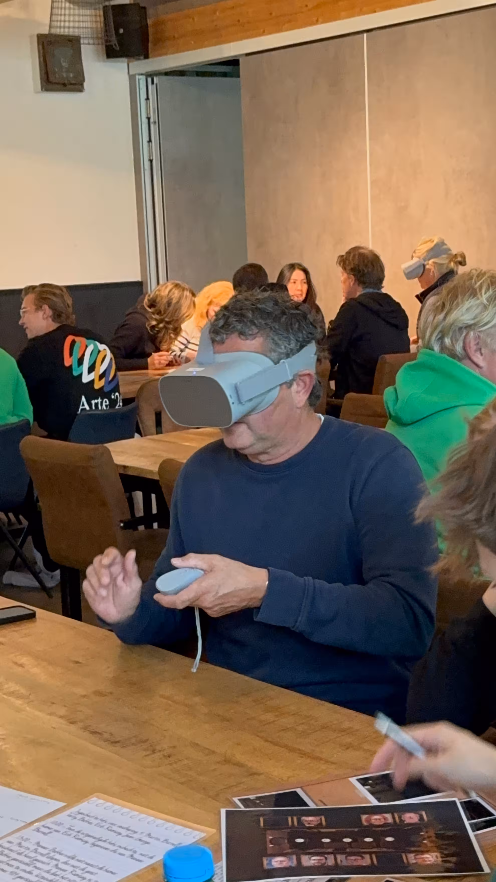 Meneer met blauwe trui is bezig met het uitvoeren van opdrachten door middel van de VR bril