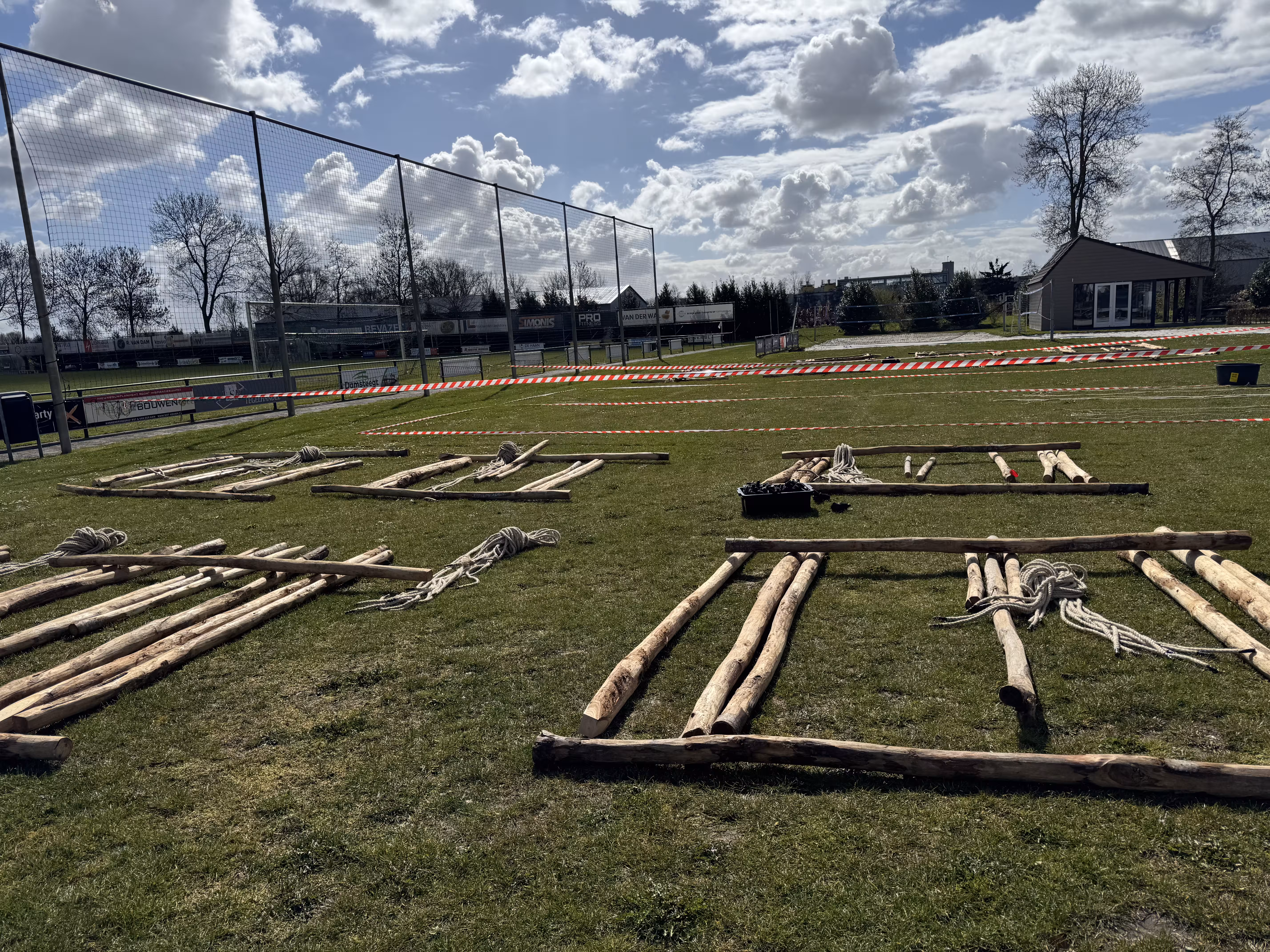 De houten balken liggen op het grasveld klaar voor een workshop katapult bouwen