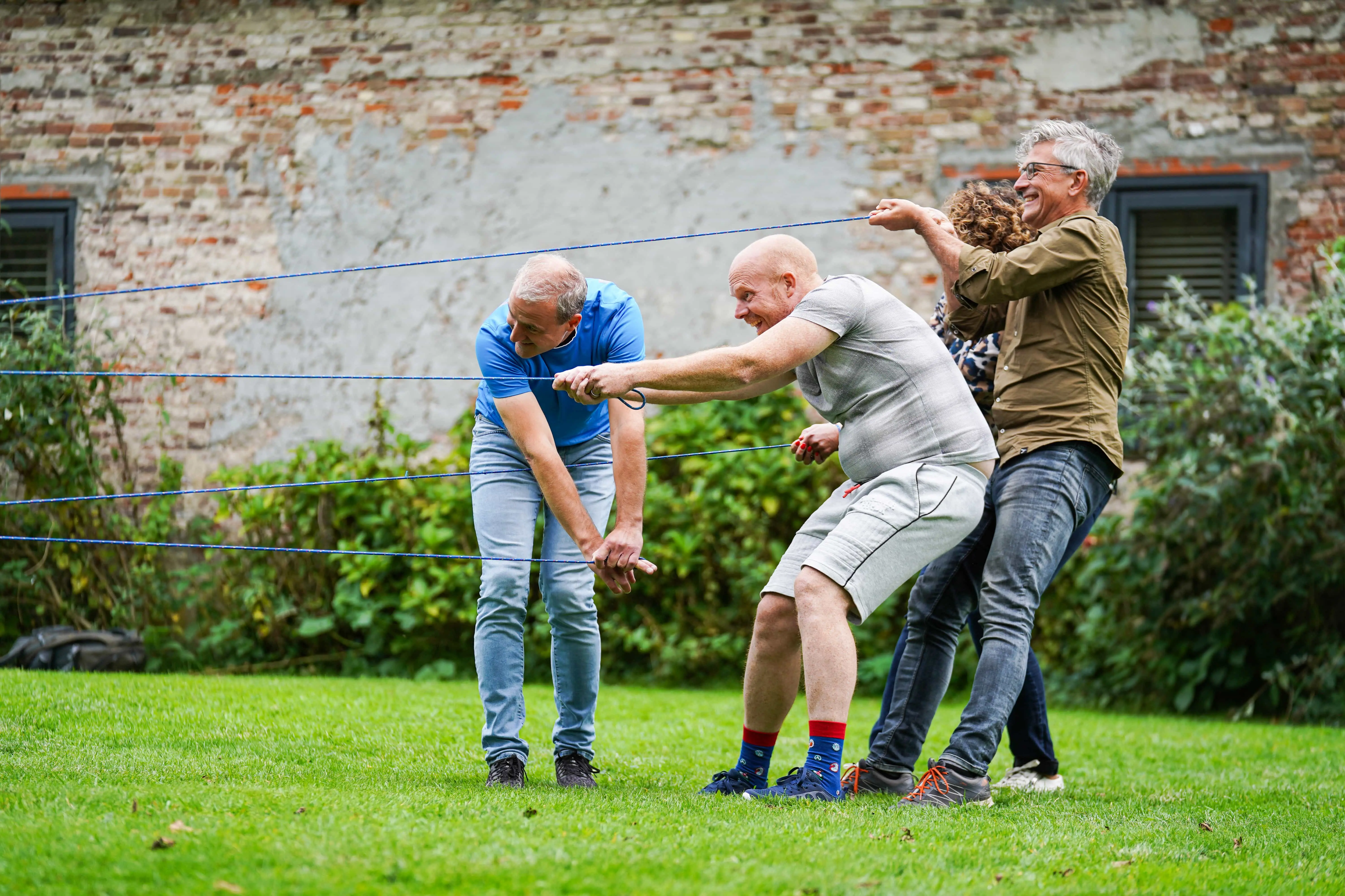 Drie mensen trekken aan touw tijdens teamopdracht