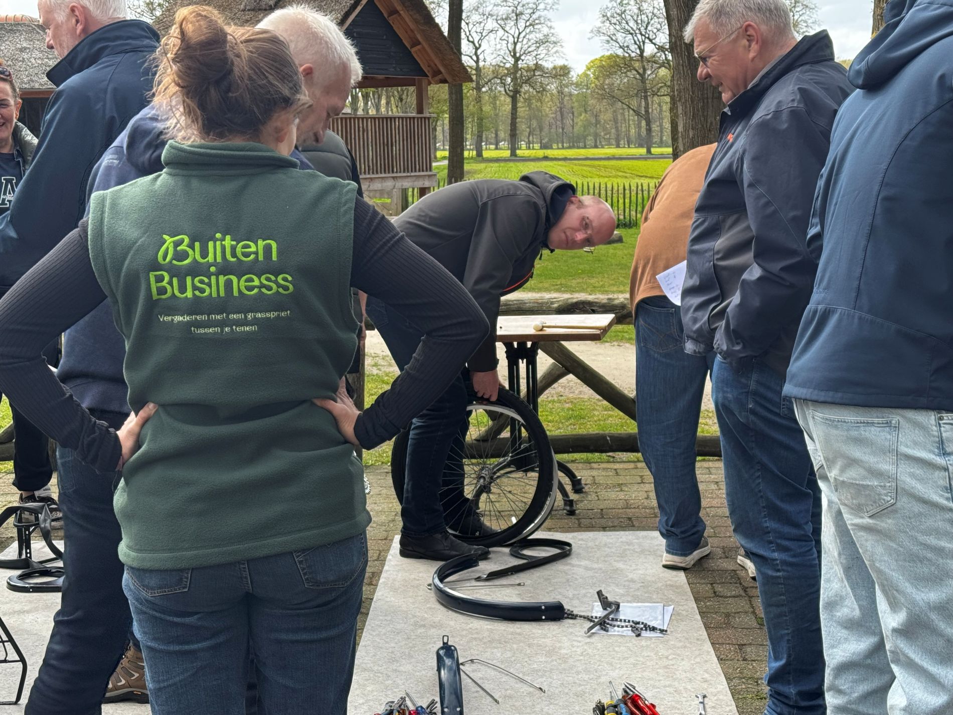 De instructeur van BuitenBusiness kijkt toe hoe de deelnemers fietsen bouwen voor Afrika