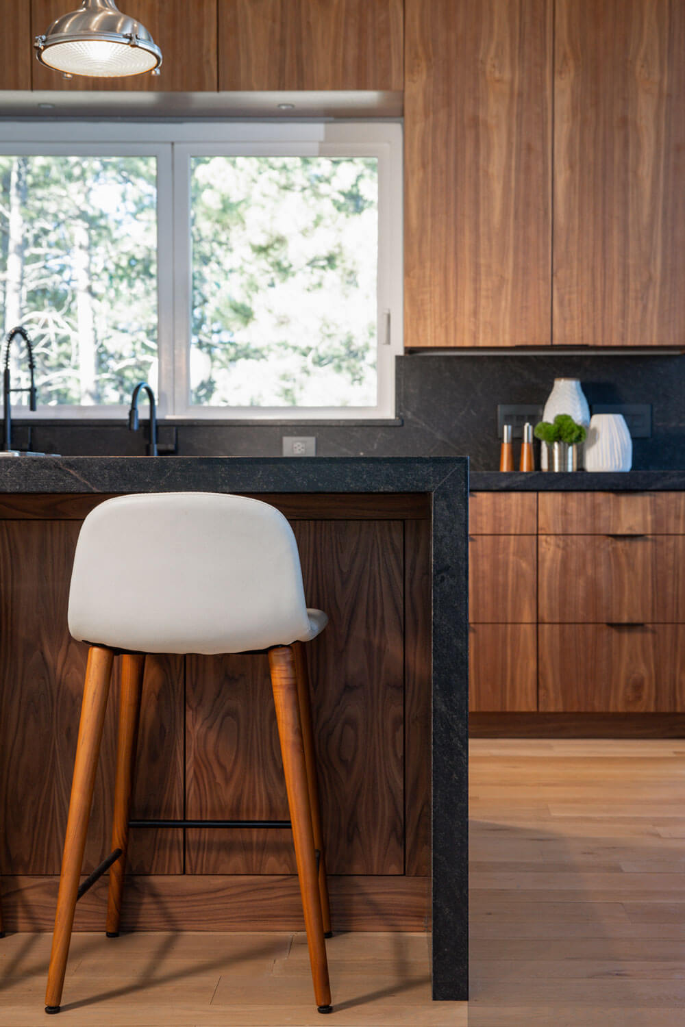 Walnut kitchen island with seating and black waterfall countertop in Evergreen Colorado