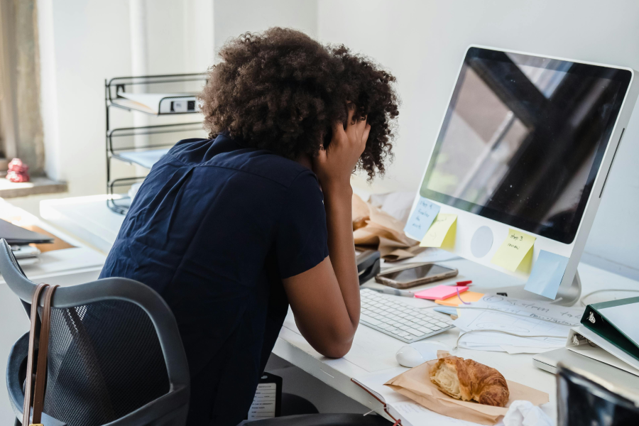 Frustrated project manager with head in hands at a cluttered desk, struggling to manage projects and tasks without the right tools.